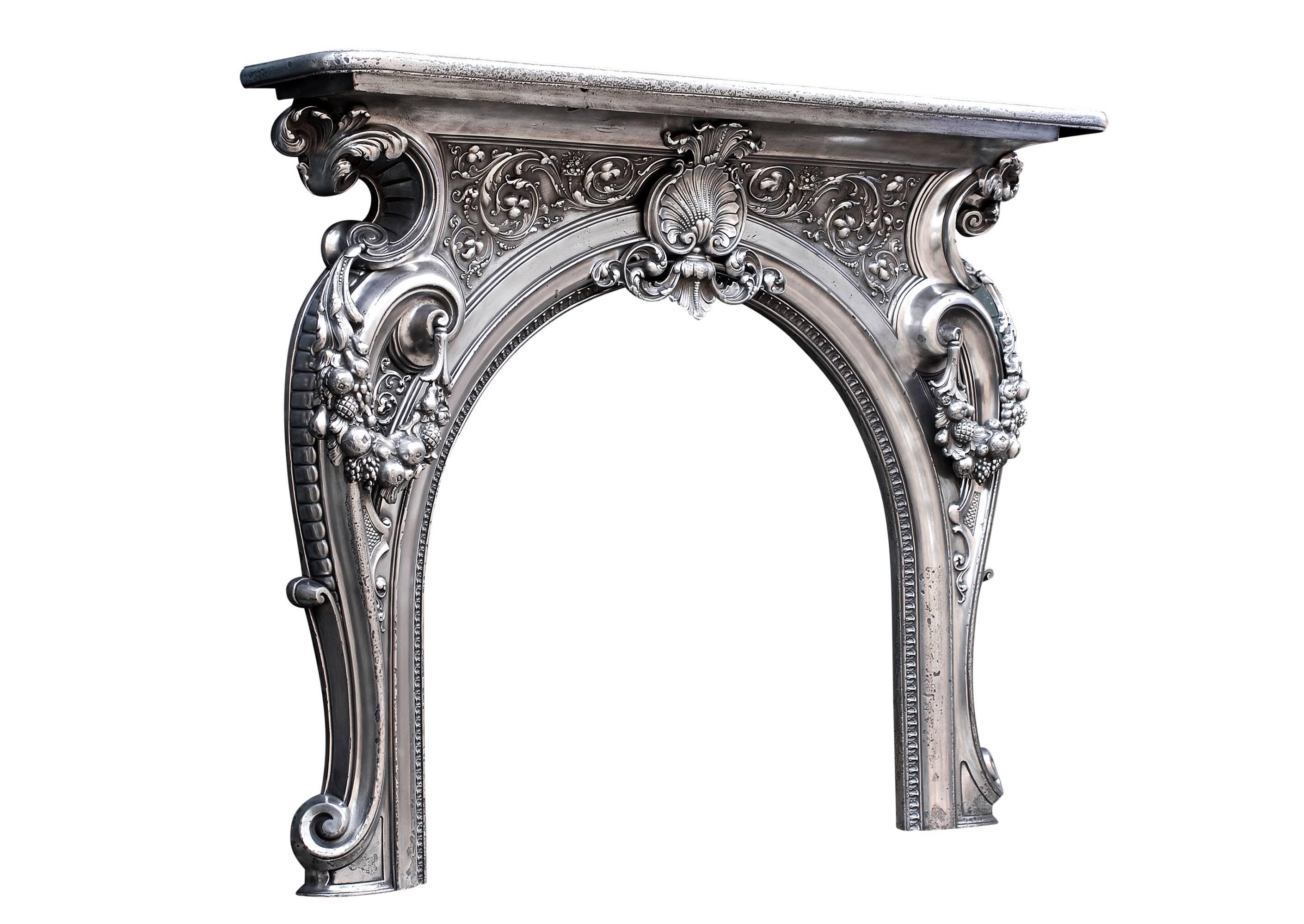An ornate 19th century French cast iron fireplace. The large shell to centre with leafwork and scrolls to either side, the legs draped with festoons of foliage and fruit with intricate moulding to arched opening.

Measurements:
Shelf Width:	1570 mm 