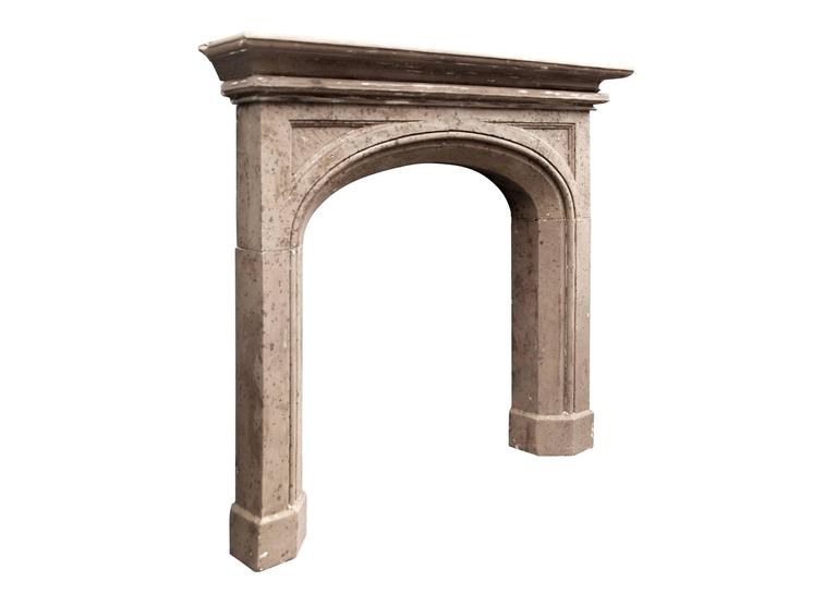 A mid-late 19th century English Gothic style stone fireplace. The moulded jambs surmounted by arched frieze with spandrel panels. Two-tier moulded shelf. Some markings to the stone caused by the painting of the fireplace over the years.

Measures: