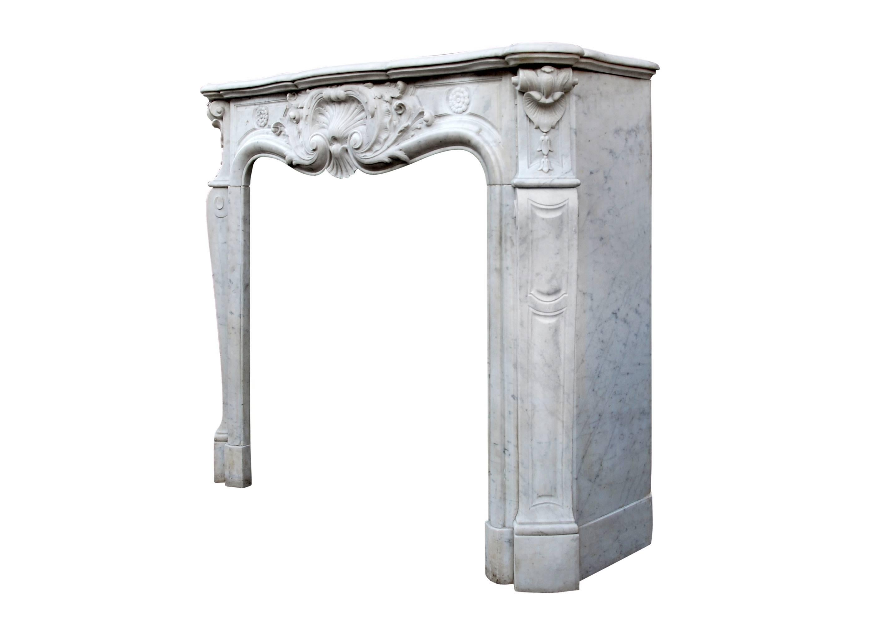 A very well carved Carrara marble Louis XV fireplace, the panelled frieze with carved shell and scrolls to centre with trailing foliage and rosettes. Shaped panelled jambs with carved shell and bellflowers to side blockings. Serpentine shaped shelf.