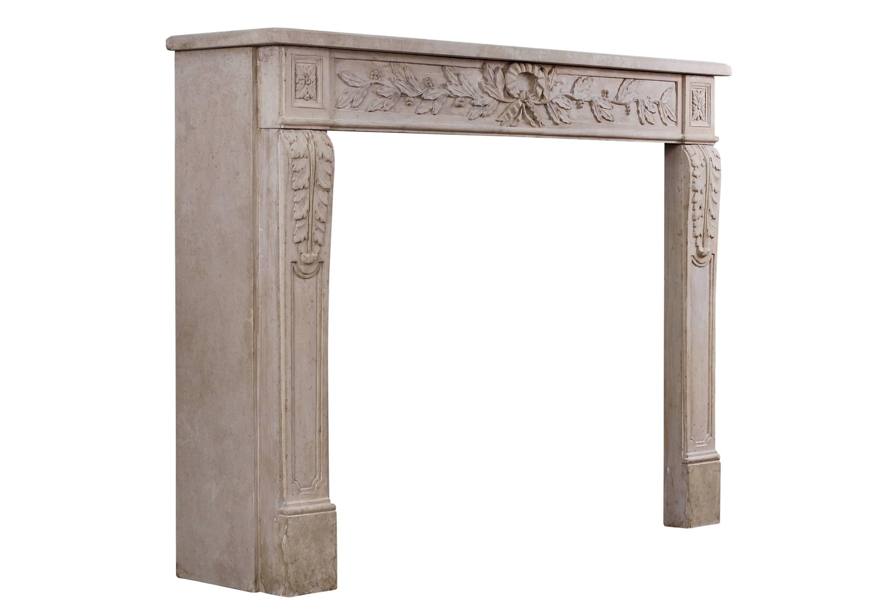 An unusually ornately carved French limestone fireplace in the Louis XVI style. The panelled jambs with gently shaped acanthus leaves surmounted by square carved end blockings. The frieze with centre ribbon, carved berries and foliage throughout,