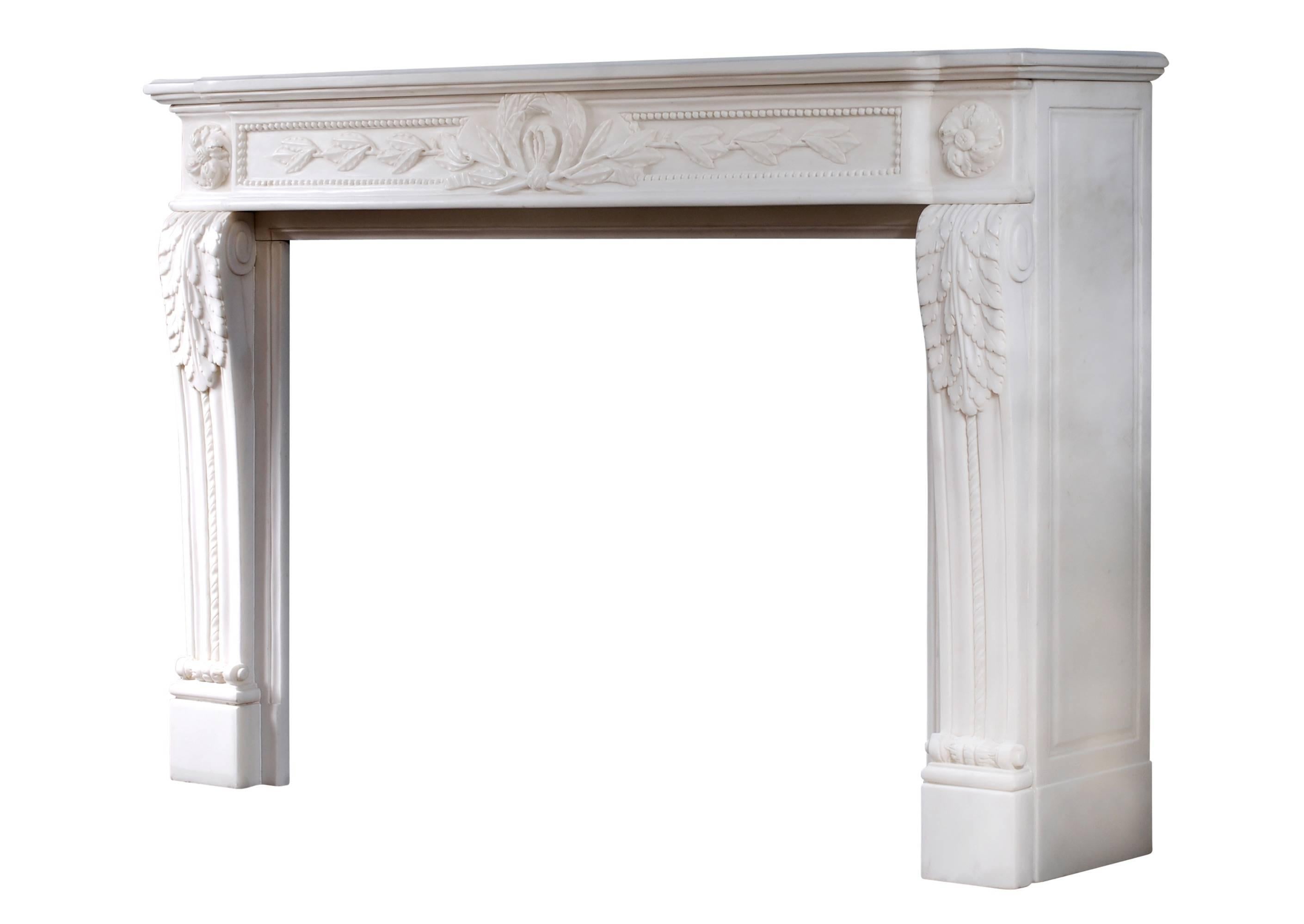 A French Louis XVI style pure white marble fireplace. The shaped frieze with carved garland and ribbon centre with trailing leaves and beading either side, the jambs with carved acanthus leaves with rope moulding surmounted end blockings with