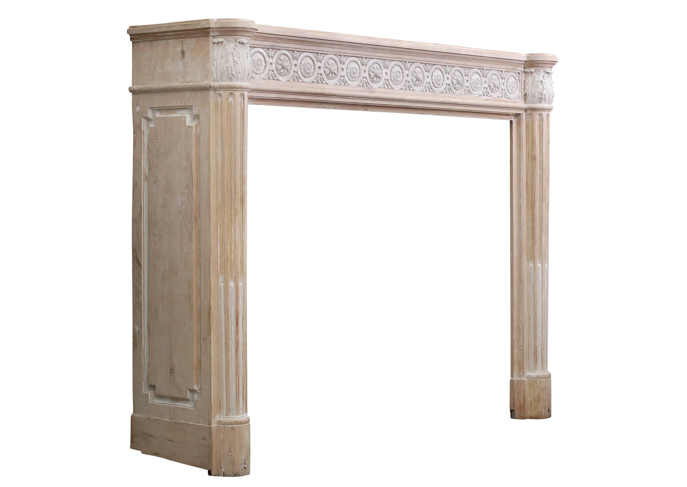 A French Louis XVI style wood fireplace with composition enrichments. The stop-fluted jambs with tapering, half rounded columns, surmounted by finely carved acanthus leaf capitals. The frieze with guilloche composition throughout. Moulded, shaped