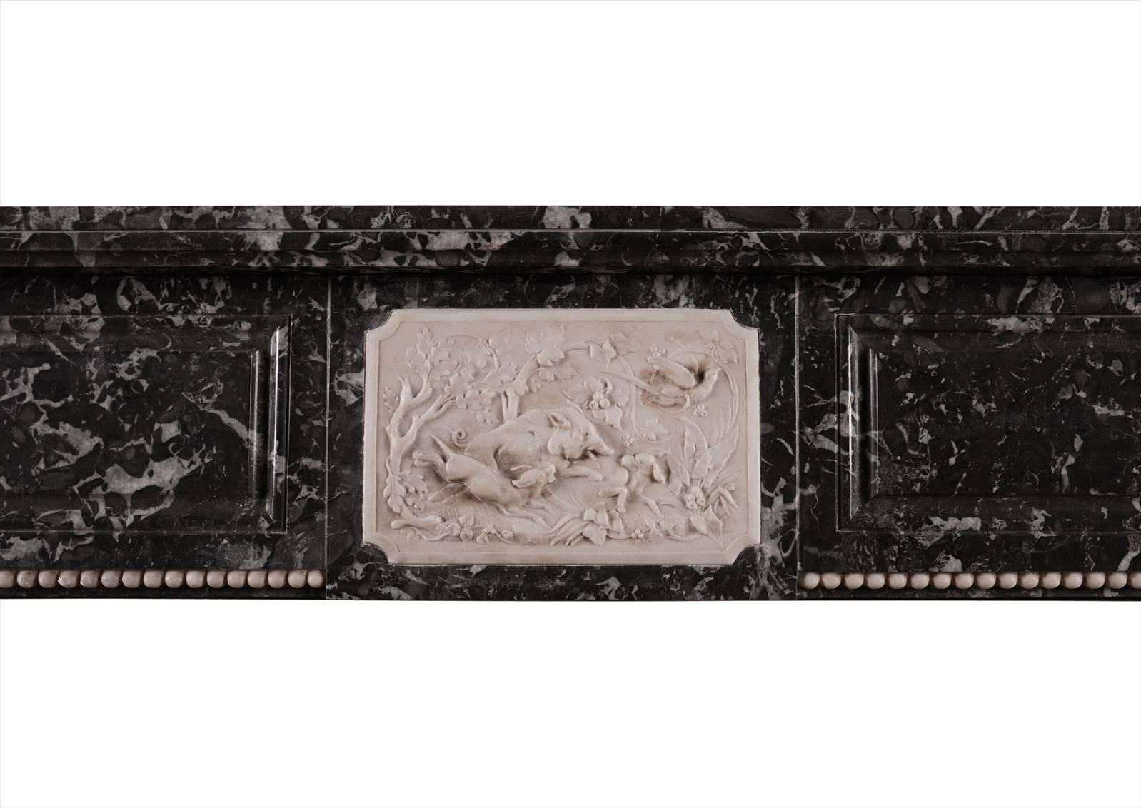 Une charmante cheminée Louis XVI en marbre Sainte Anne des Pyrénées avec de délicates sculptures blanches. Le panneau central présente une scène de chasse au sanglier, des chiens, des oiseaux et des fleurs. Les montants et le blocage latéral sont