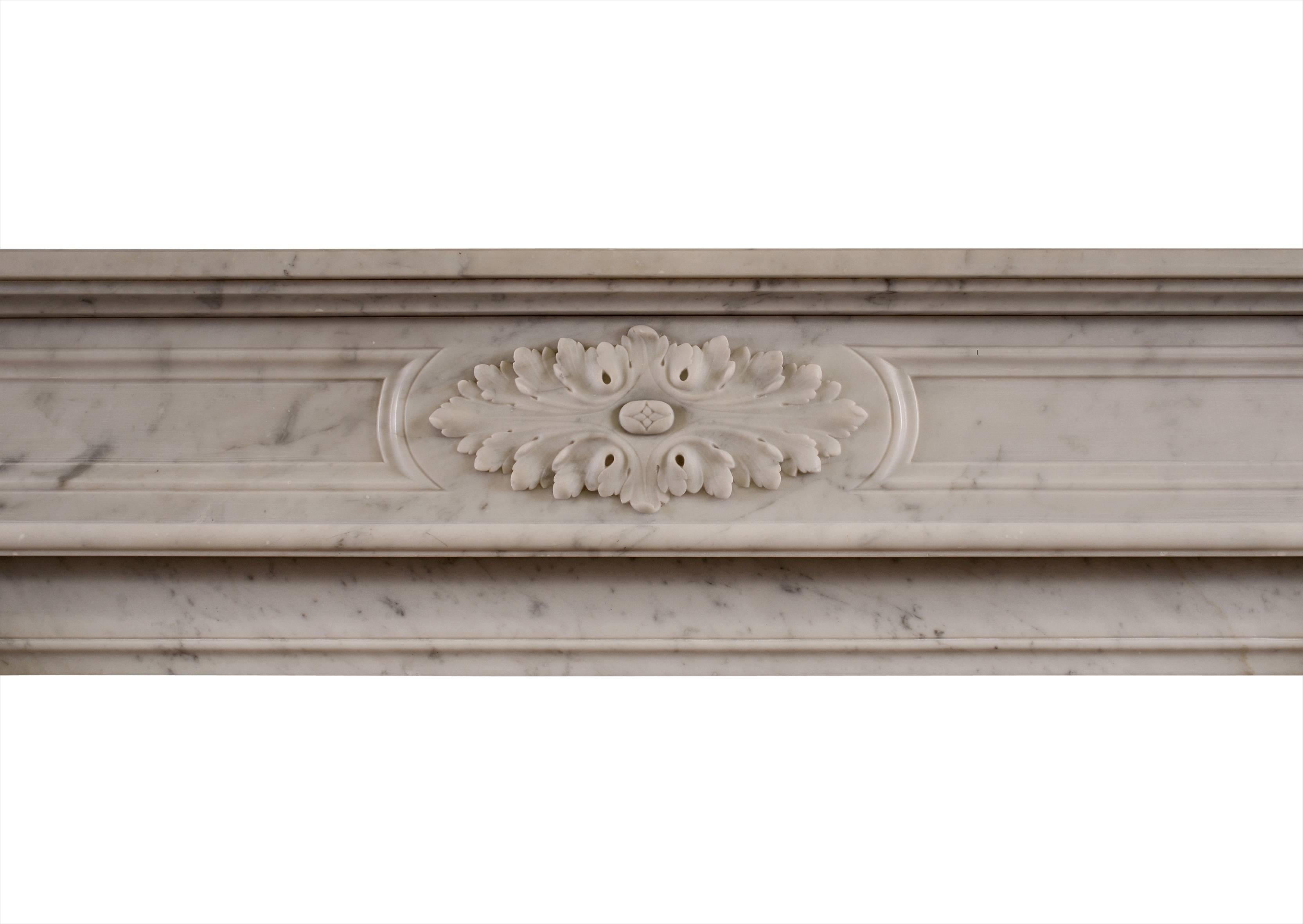 A 19th century French Louis XVI style fireplace in Carrara marble. The moulded jambs with attractive acanthus leaves and scrolled returns, the frieze with carved oval paterae, moulded panels and square paterae to side blockings. Breakfront