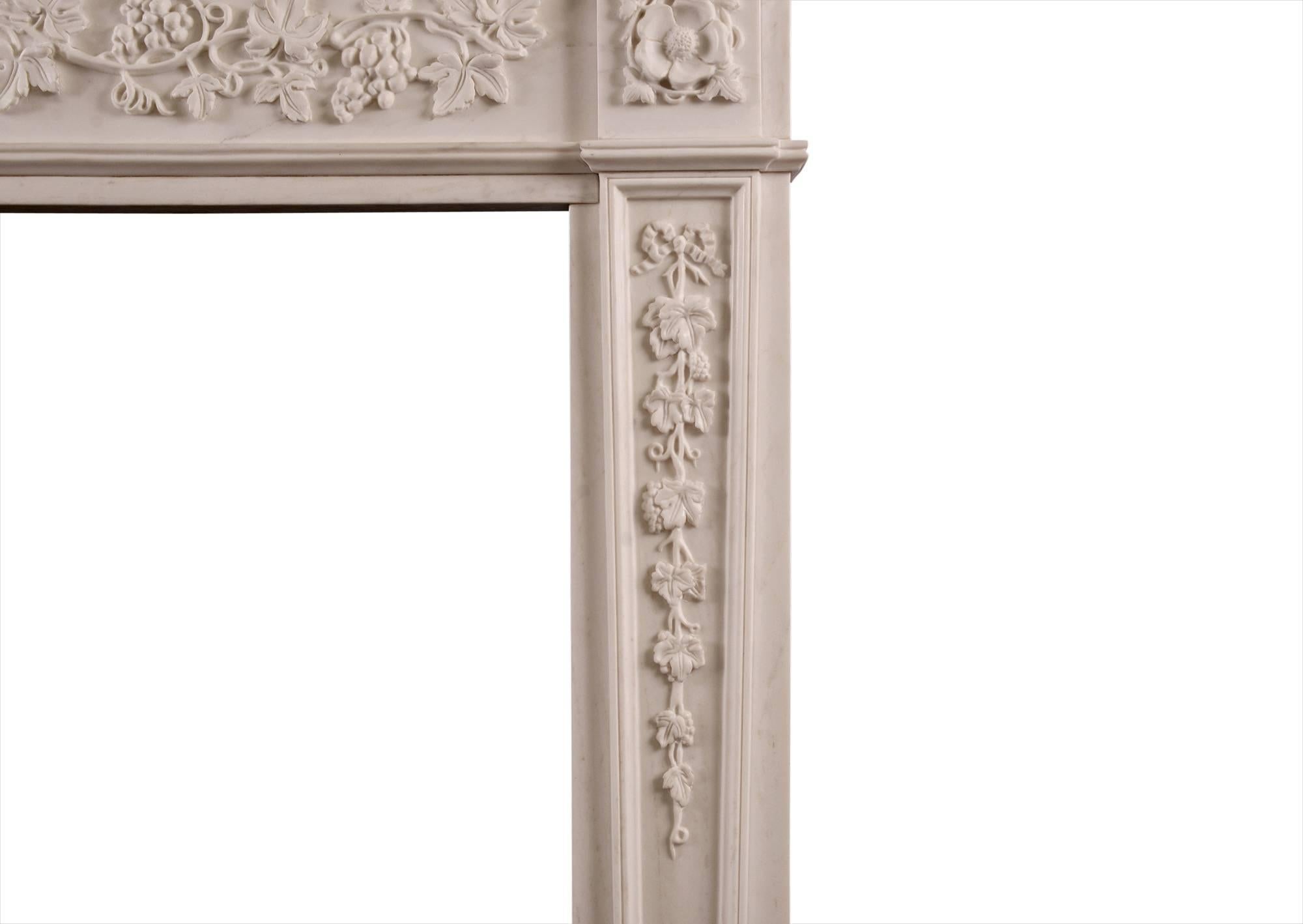 An attractive English Regency style white marble fireplace. The frieze with flowing vines and grapes, and the jambs with tapering pilasters with tie ribbons with vine leaves trailing below. The side blockings with unusual flower motif paterae. The
