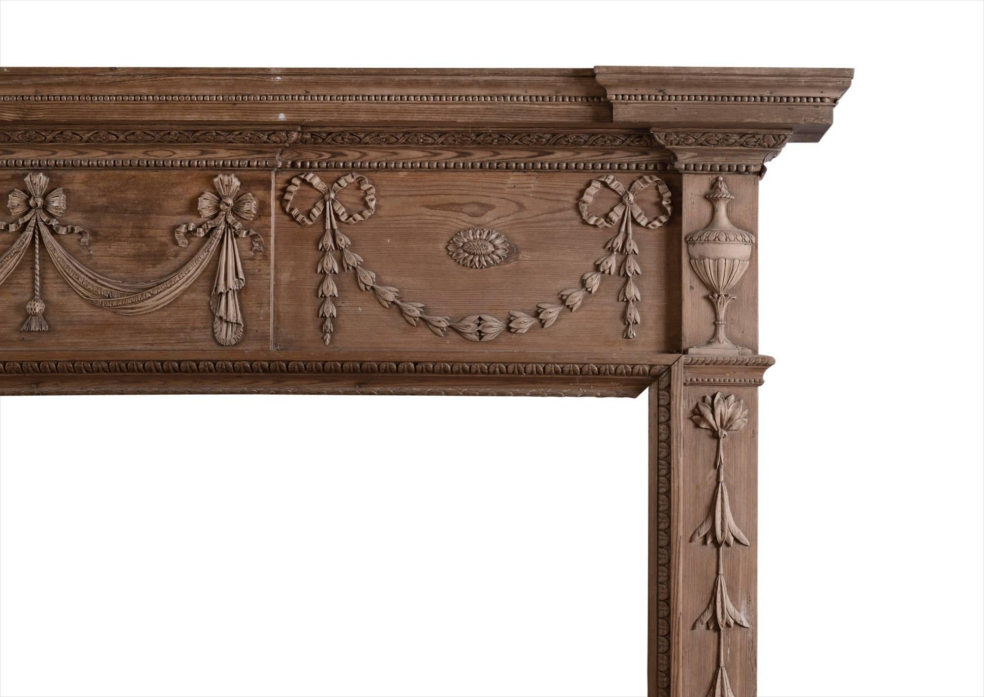 A good quality pine fireplace in the Georgian style. The legs with carved bell flowers, surmounted by classical urn. The frieze with swags, drapery and tied ribbons, surmounted by moulded shelf with decorative beading, English, 19th century.

Shelf