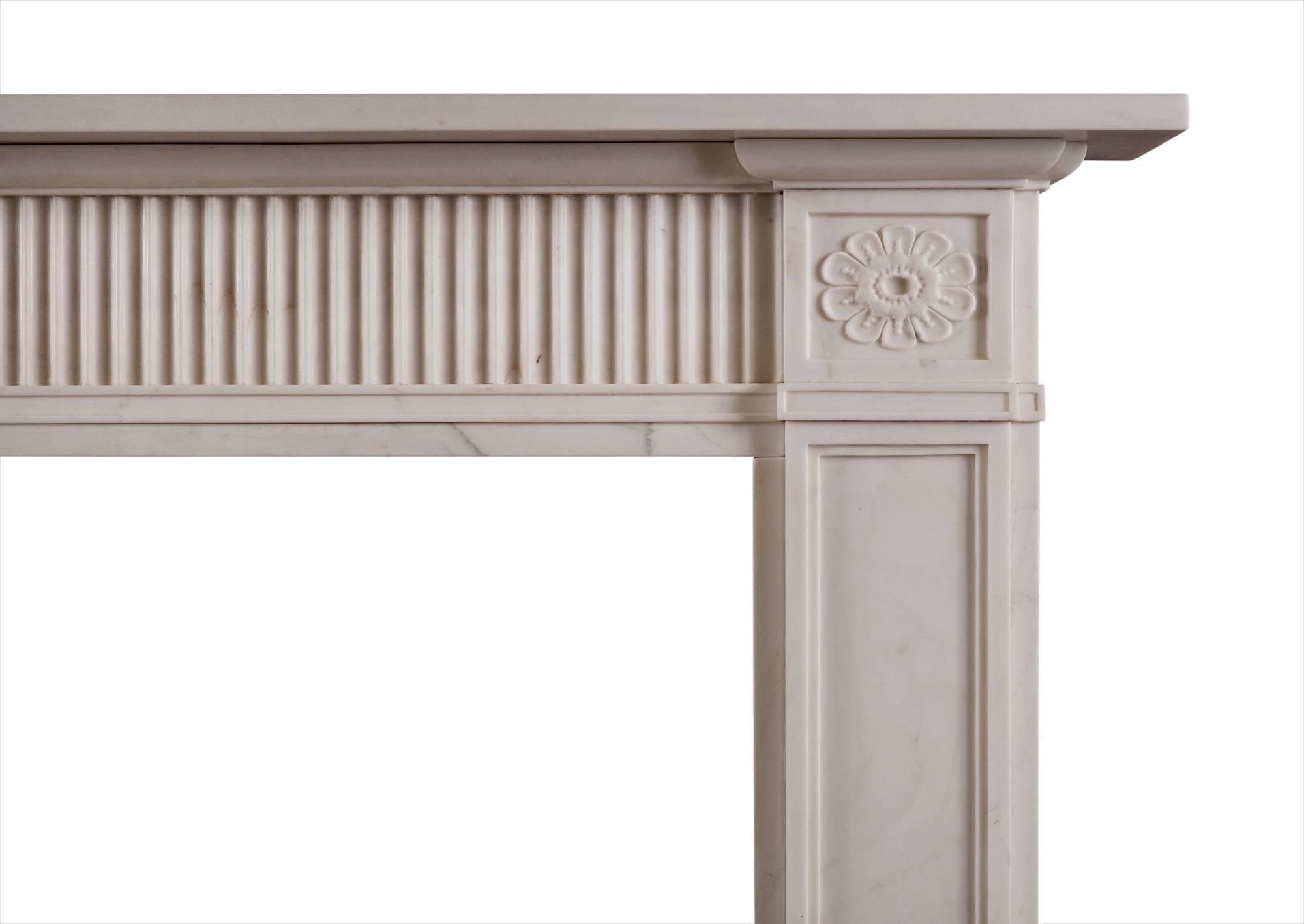 An elegant late 18th century style white marble fireplace, with fluted frieze and panelled jambs. The side blockings beautifully carved with delicate flowers. Attractive moulding beneath frieze and blockings. A copy of a period original (circa 1790