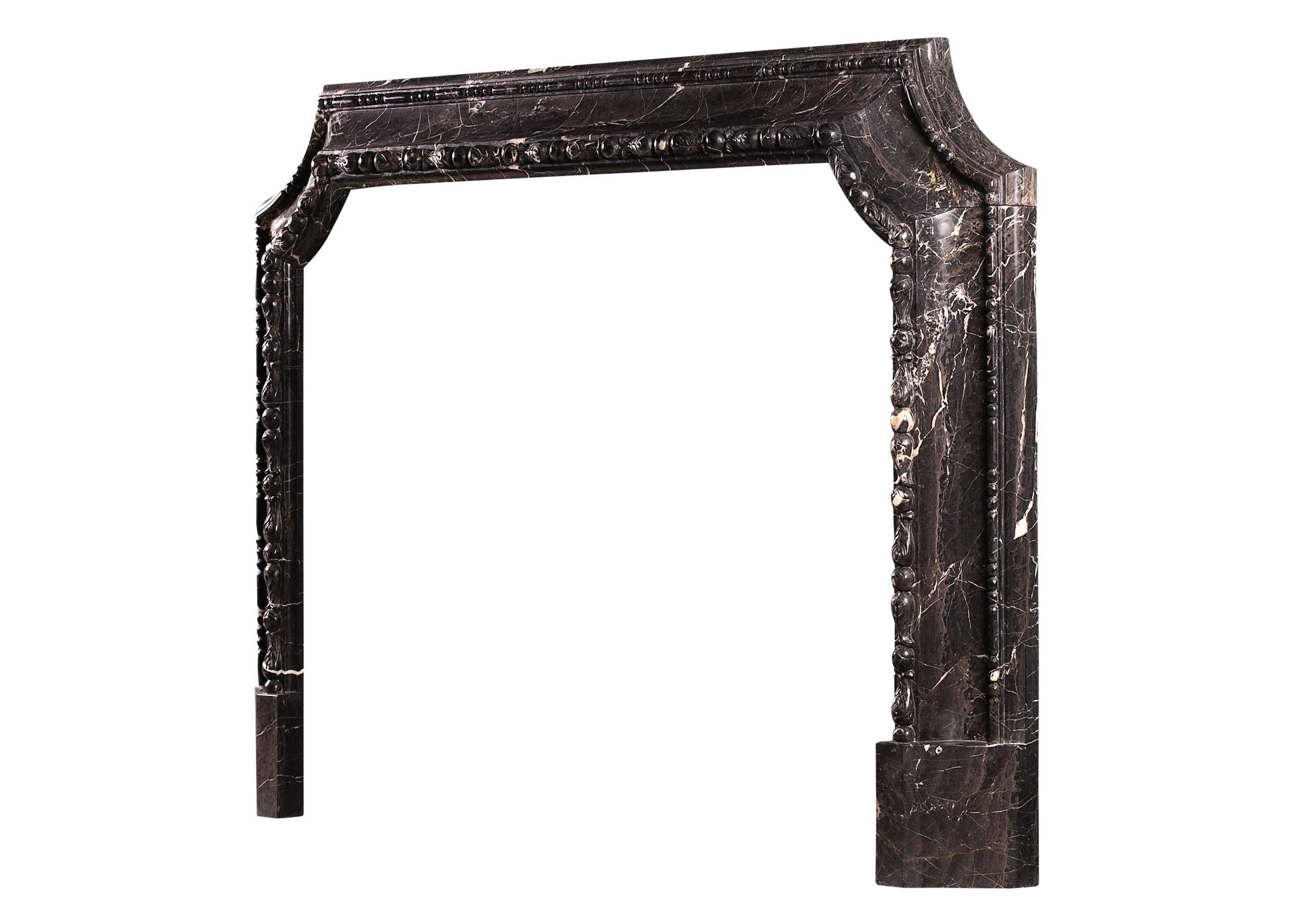 An unusual Queen Anne style moulded fireplace in Bruno Marquina marble. The inner moulding with carving throughout, the outer moulding with beading. A modern copy of an earlier piece (shelf length given is overall width of jambs, shelf depth is