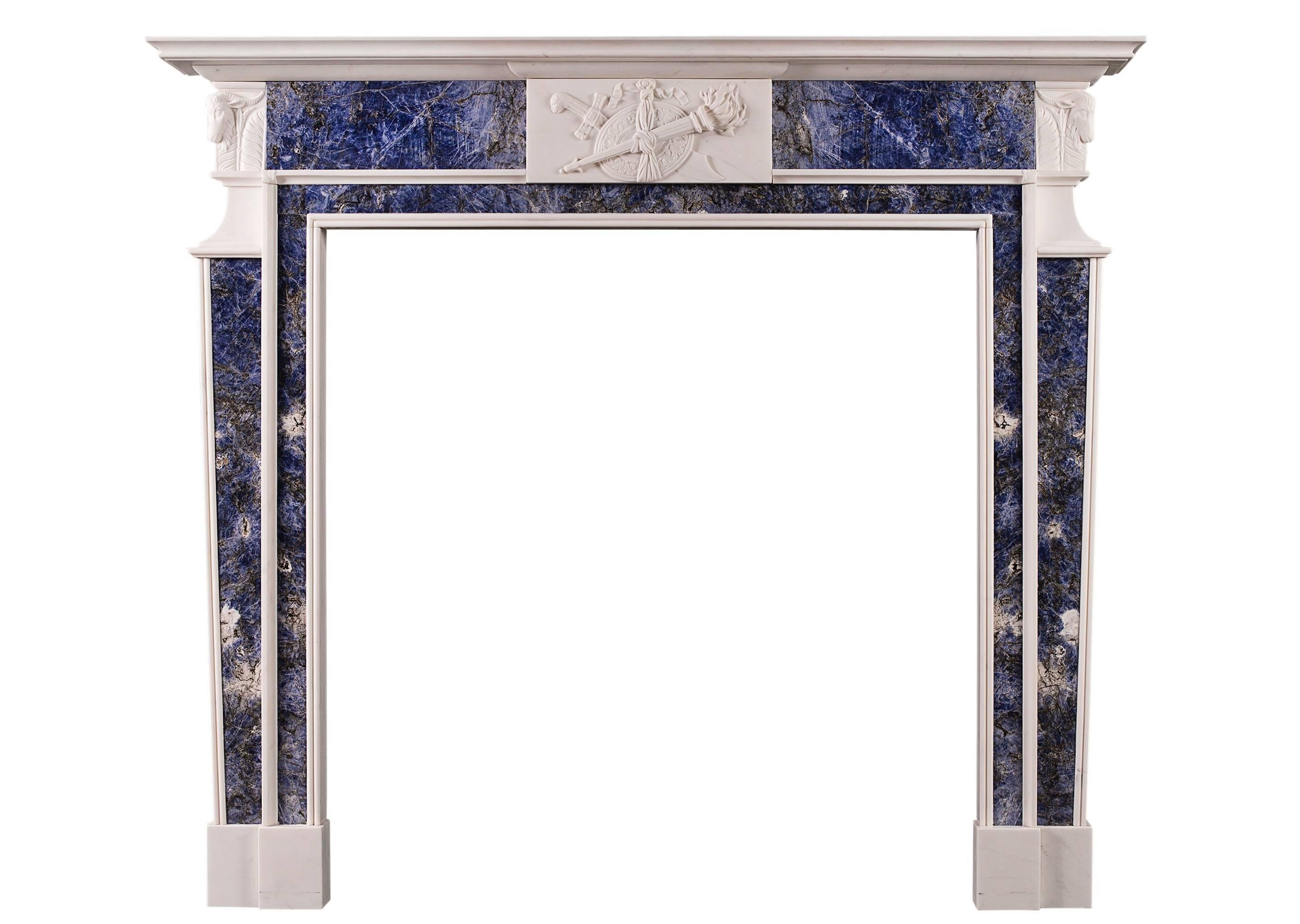 A charming late Georgian style carved white marble fireplace with striking rich blue marble inlay. The centre tablet finely carved with torch, sword, shield and ribbons. The side blocking embellished with angled rams heads and acanthus leaves. A