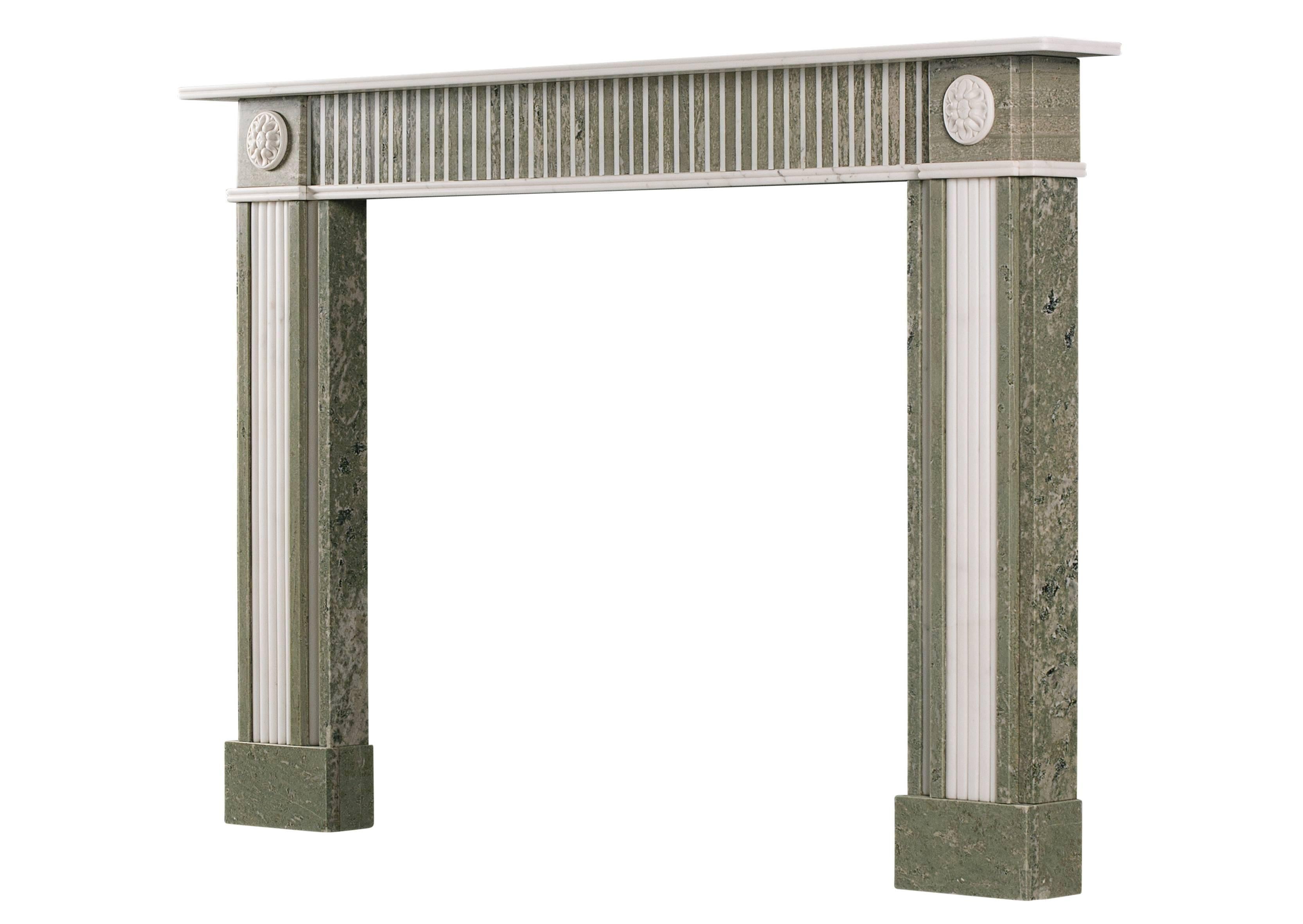 A Regency style fireplace in Swedish green marble with white marble inlay. The jambs with convex flutes, surmounted by carved oval paterae. The frieze with full flutes, contrasting the two marbles. Reeded shelf above. English, early 20th