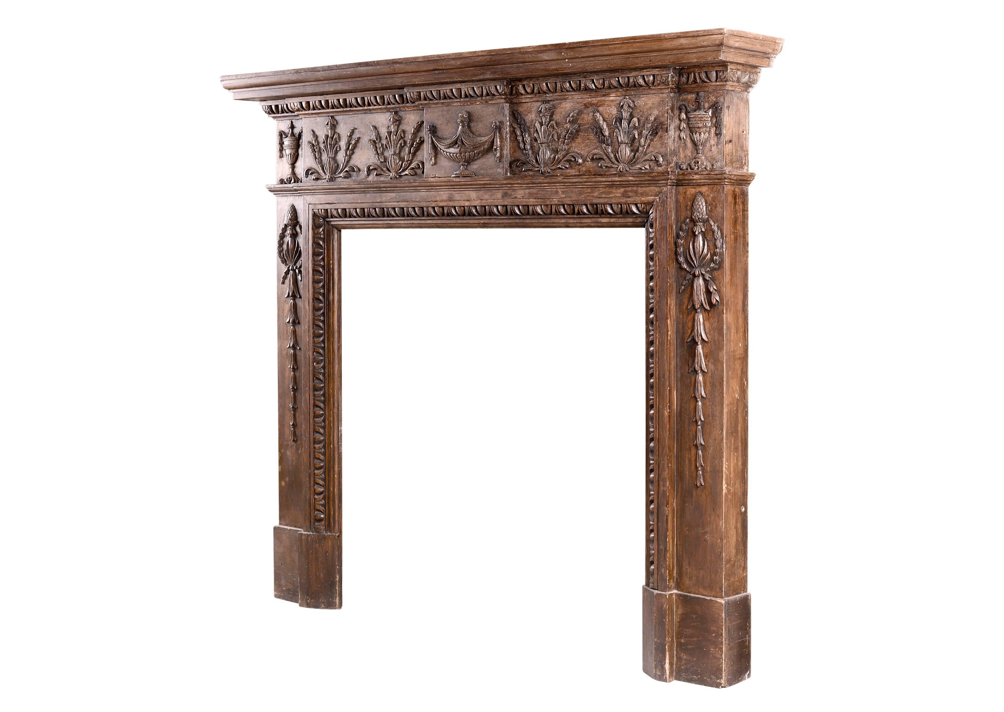 A 19th century English wood fireplace. The carved frieze featuring urns to centre block flanked by Athemion foliage. The jambs with carved belldrops, acorns and floral wreaths. Egg and dart moulding to ingrounds.

Shelf width - 1492 mm 58 ¾