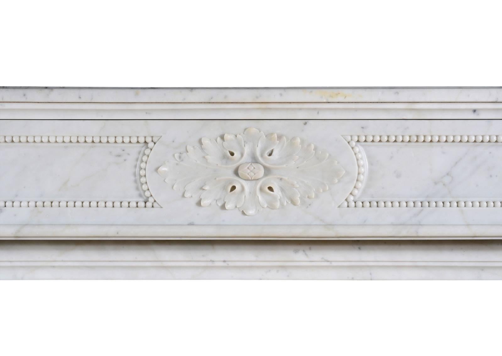 Ein hochwertiger französischer Kamin im Louis-XVI-Stil aus hellem Carrara-Marmor. Der geformte Fries mit geschnitzten ovalen Paterae in der Mitte und durchgängigen Wülsten. Die Pfosten mit geschnitzten Akanthusblättern und spiralförmiger