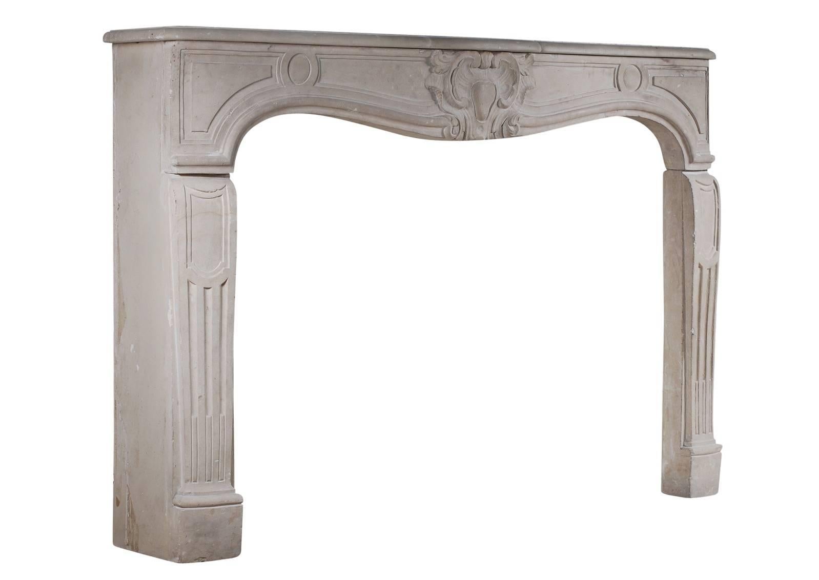 A 19th century French limestone fireplace in the Louis XV style. The panelled, carved frieze with cartouche to centre, the shaped jambs with stop-flutes and panels. Shaped shelf. Good patination of stone. (Near pair to 3790)

Measures: 
Shelf width
