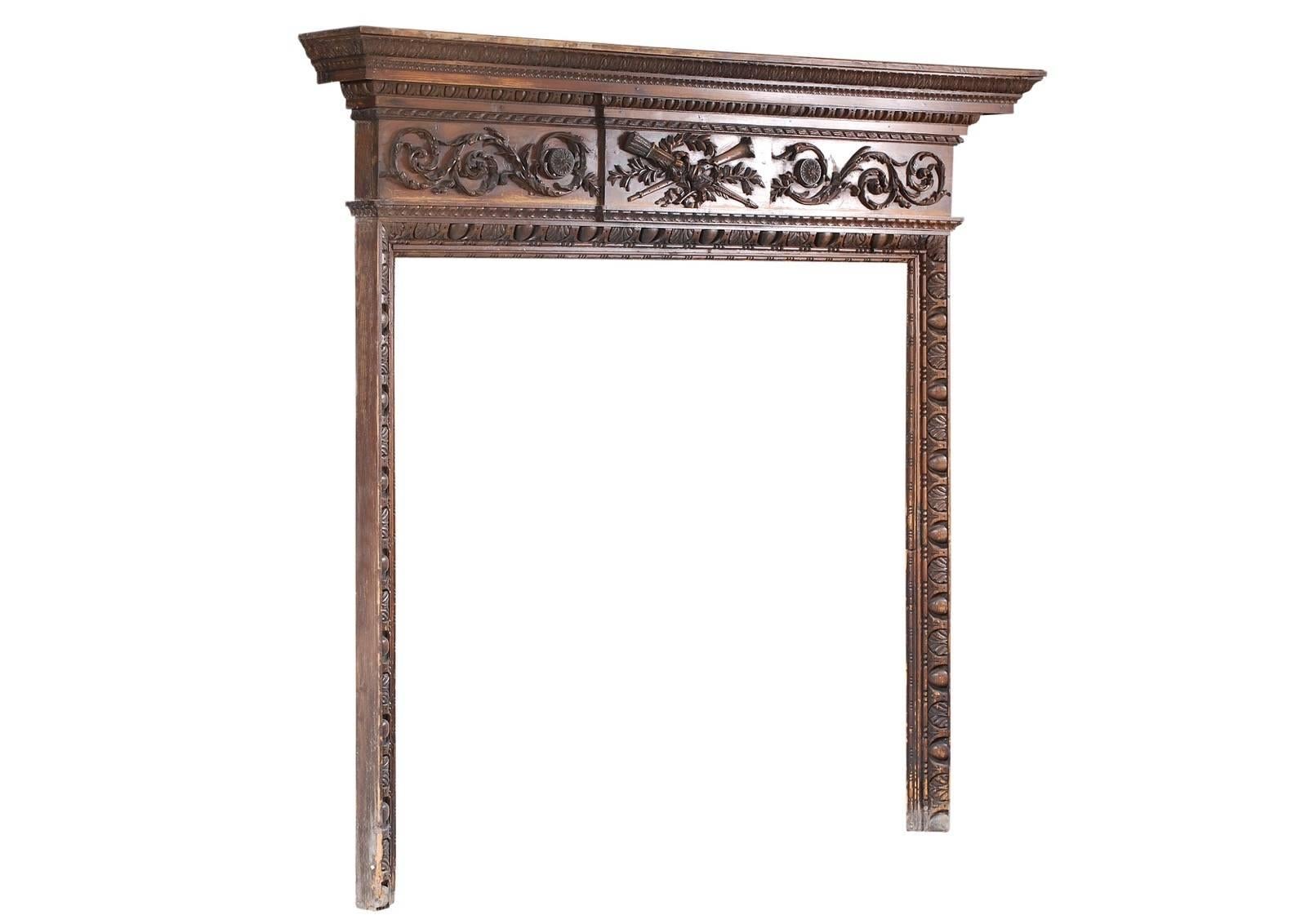 A very good quality late 18th century carved pine English fireplace. The centre panel with carved quiver, foliage and ribbons, with running scrolled foliage and paterae to frieze. Pediment shelf with egg and tongue, ribbon and stiff acanthus leaf