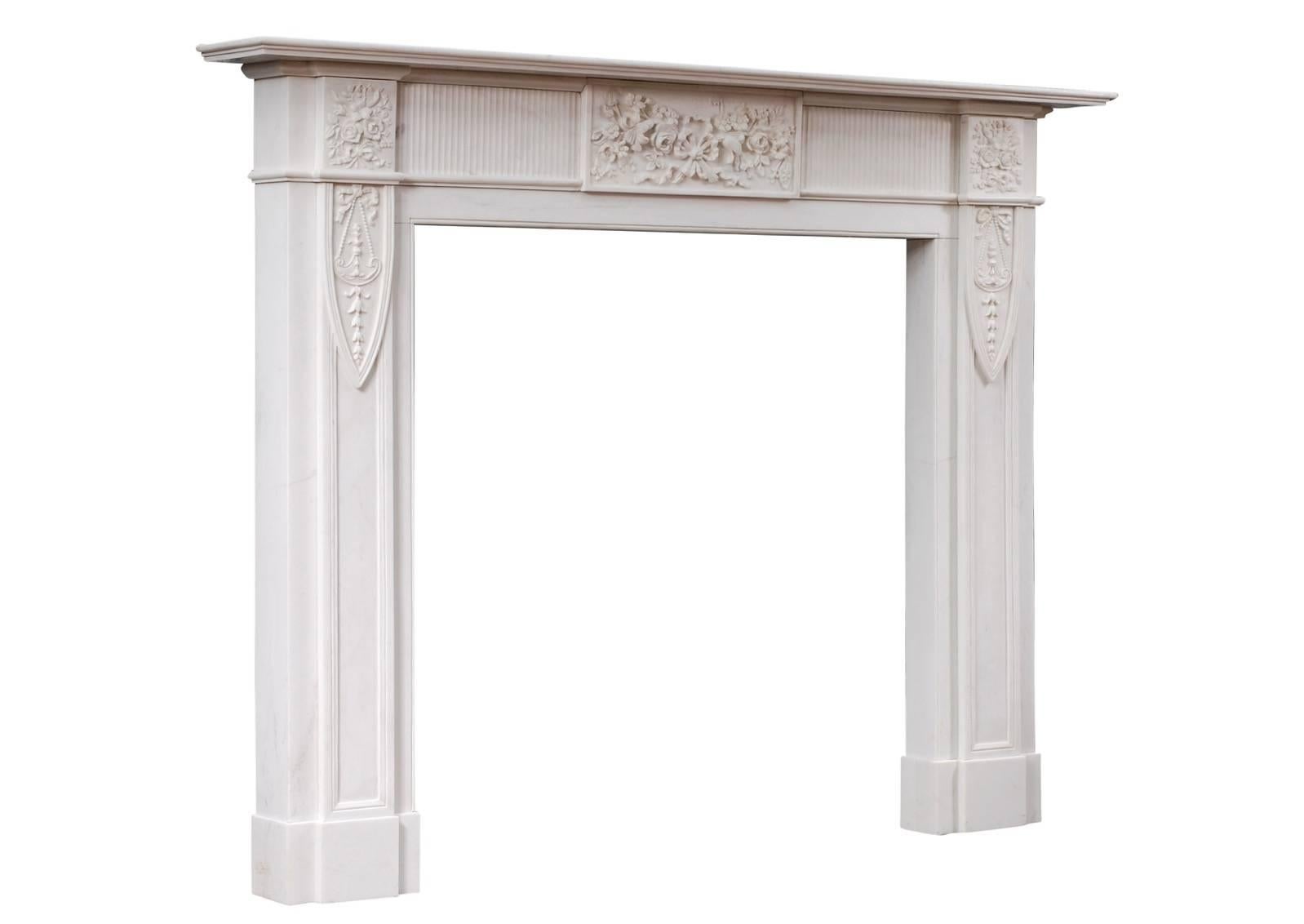 An English marble fireplace in pure white marble. The carved frieze with centre block and end blockings featuring flowers and foliage tied with ribbons. The panelled jambs carved with ribbons and belldrops. Moulded shelf.

Measures: 
Shelf width: