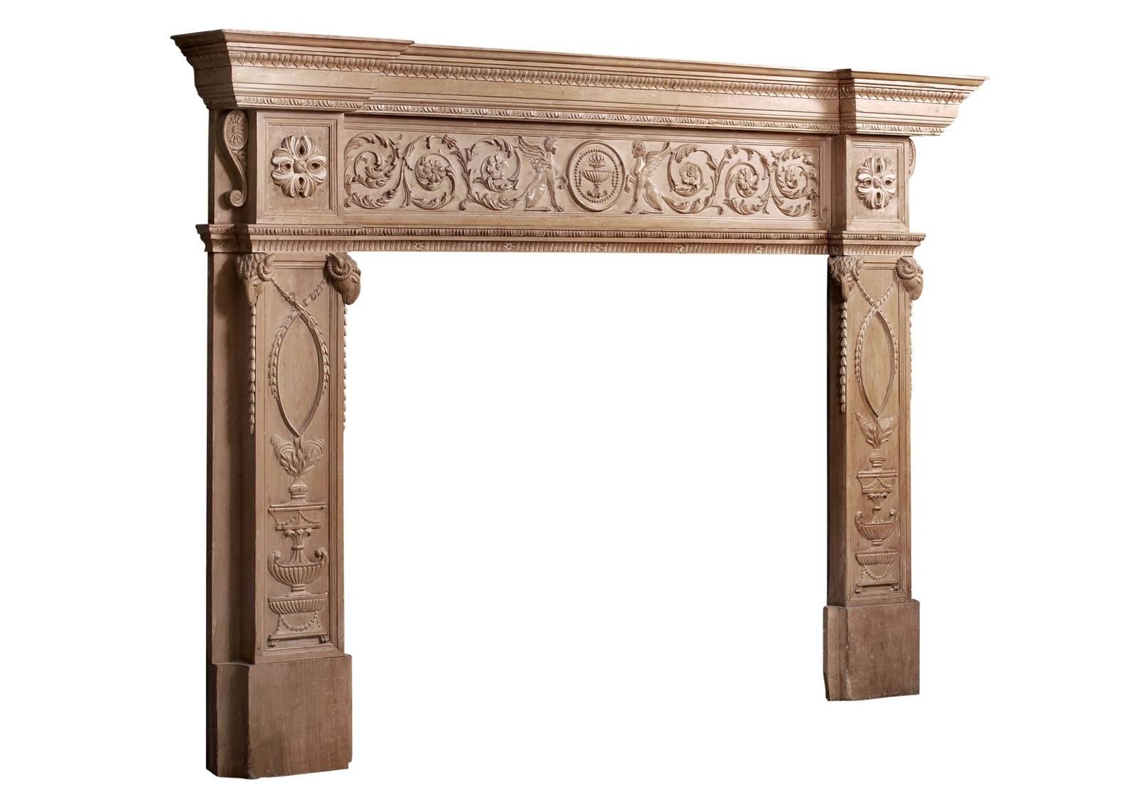 An imposing period English Regency pine fireplace. The finely carved jambs featuring urns and swags surmounted by carved rams heads, the end blockings with carved round paterae, the frieze with delicately carved floral scrolls and winged