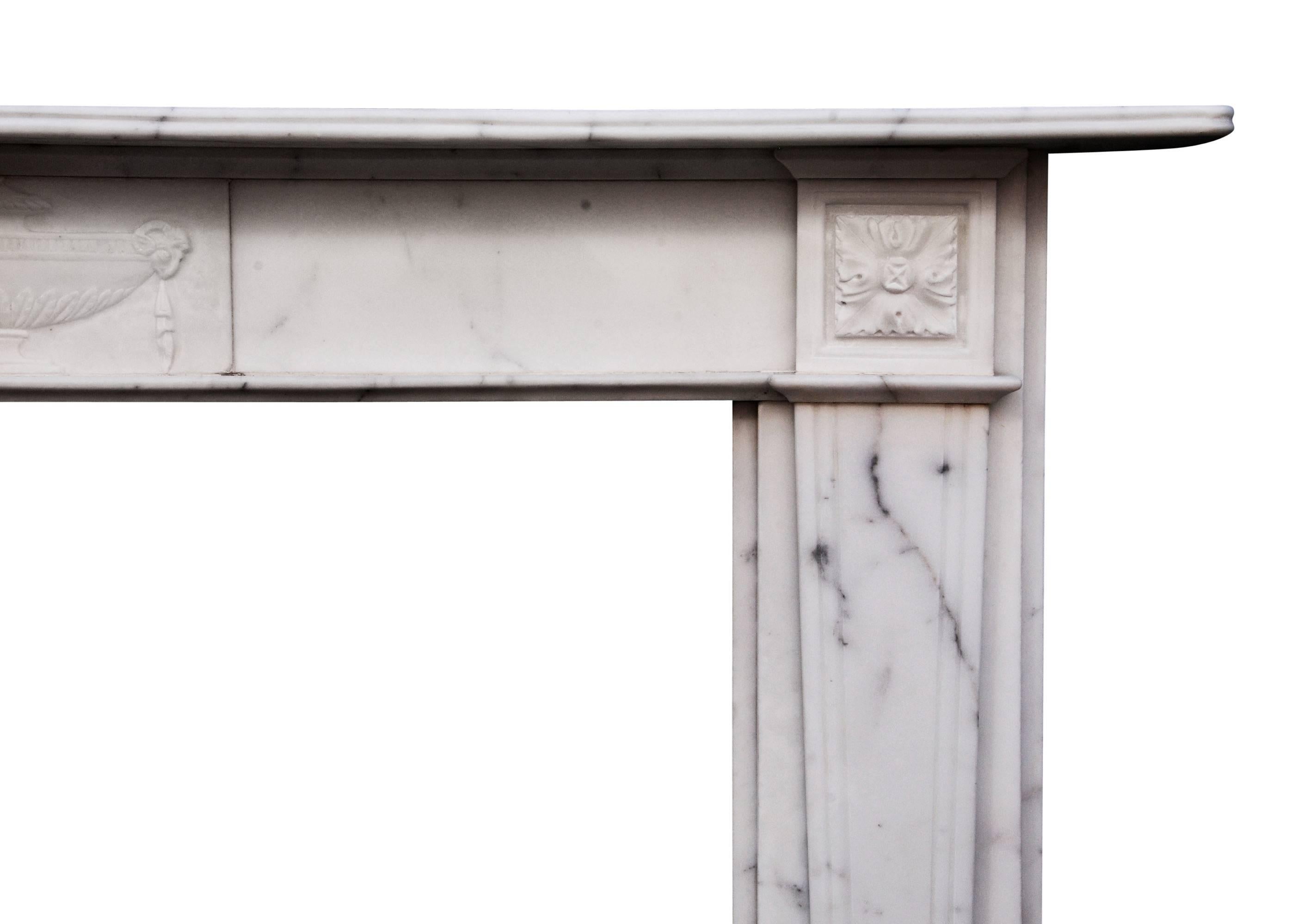 An English veined statuary marble fireplace. The carved centre tablet featuring urn with rams heads, the tapering reeded jambs surmounted by square paterae, 19th century.

Measures: Shelf width 1549 mm 61 in
Overall height 1149 mm 45 ¼