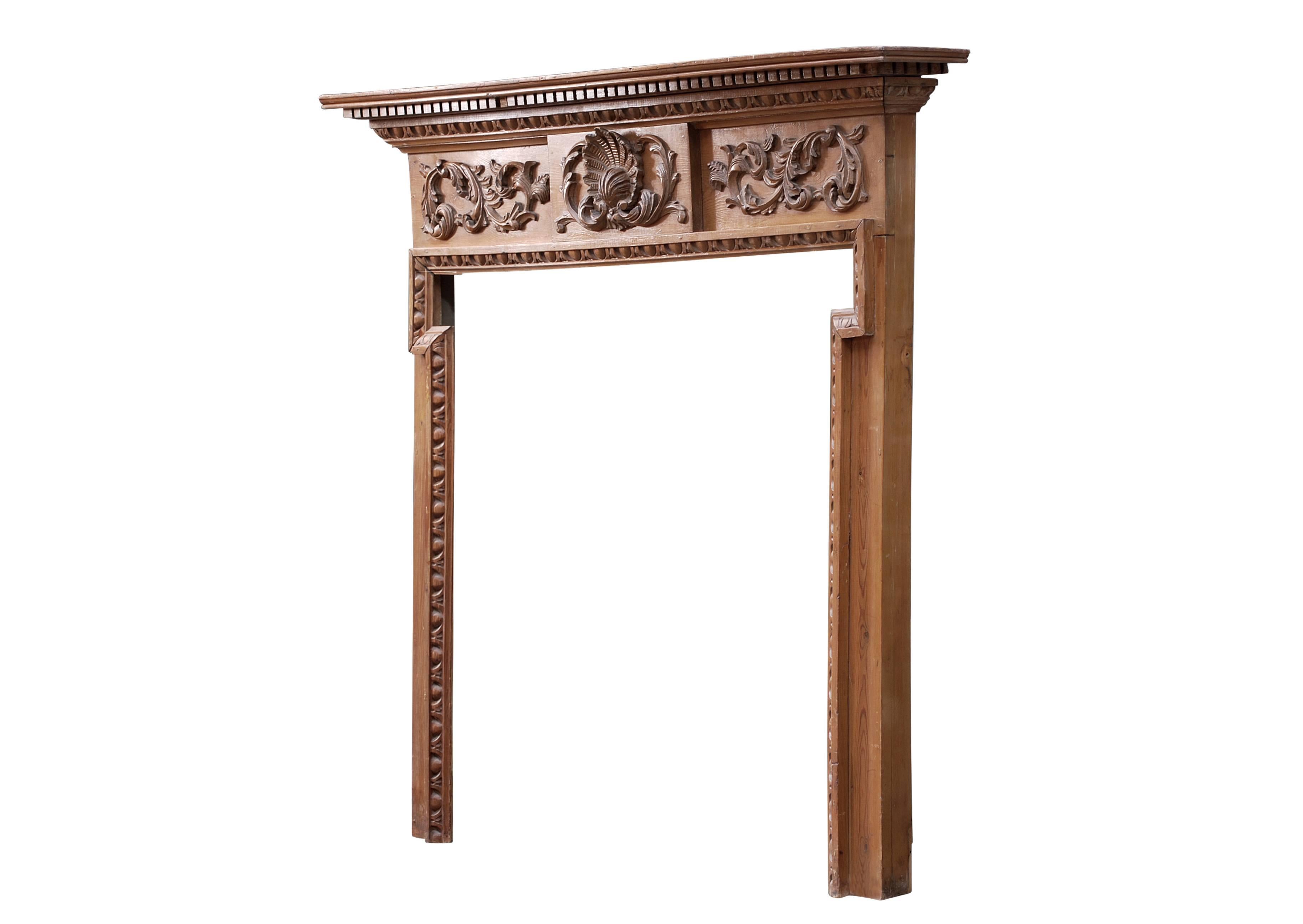 An English carved pine fireplace. The frieze with carved foliage and shell to centre, the jambs with egg-and-tongue moulding to inside, the shelf with matching egg-and-tongue moulding surmounted by dentils, 2th century. (Could be stained to any