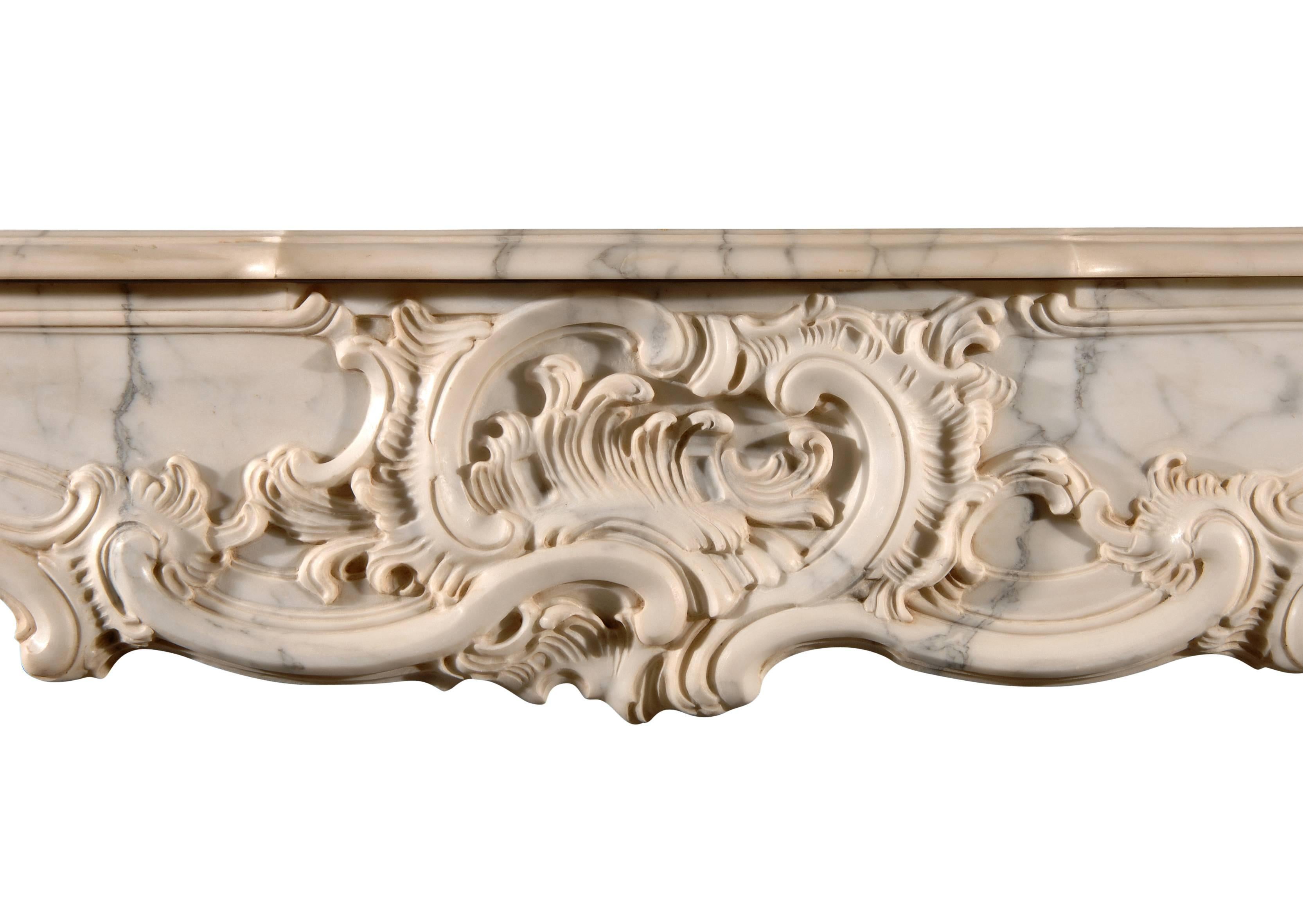 A French Provençale style Arabescato marble fireplace, with ornately carved Rococo frieze and jambs of scrolls and foliage. Unusually high for a French fireplace.

Measures: 
Shelf Width:	1770 mm      	69 5/8 in
Overall Height:	1405 mm      	55 3/8