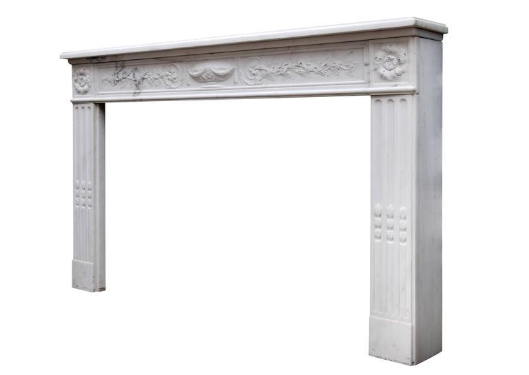 A fine quality 18th century French Louis XVI statuary marble fireplace, the frieze delicately carved with running frieze of foliage and berries with urn centre. Fluted jambs with carved husks, surmounted by paterae. Square moulded