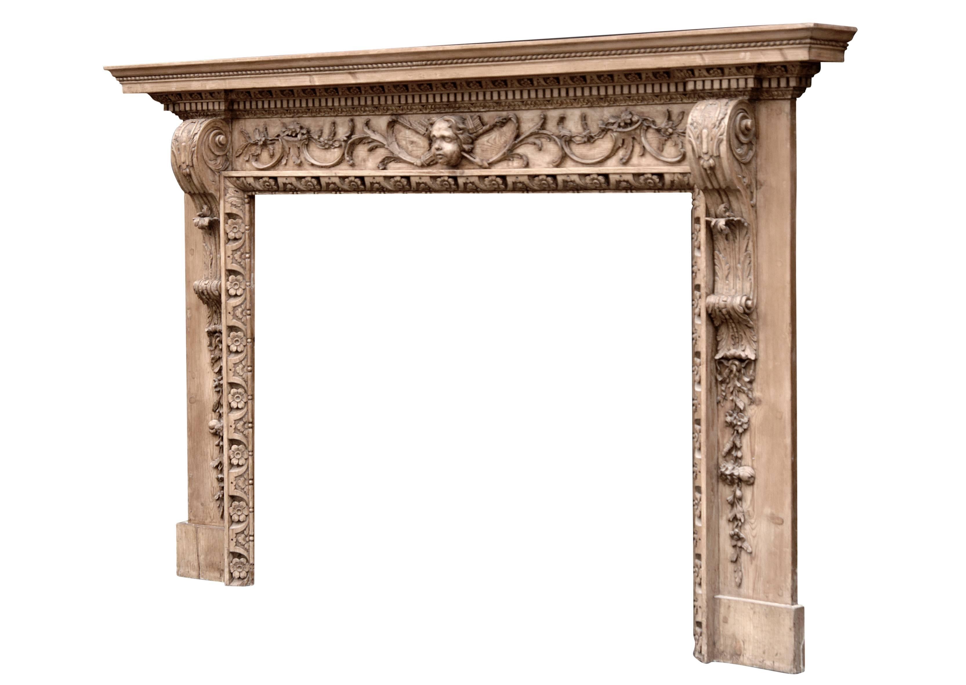 A fine quality mid-18th century (circa 1750) English stripped pine fireplace, the frieze with foliage and scrolls and central mask with quiver and arrows. The jambs carved with shaped trusses with leaf and fruit drops below. The inner moulding of