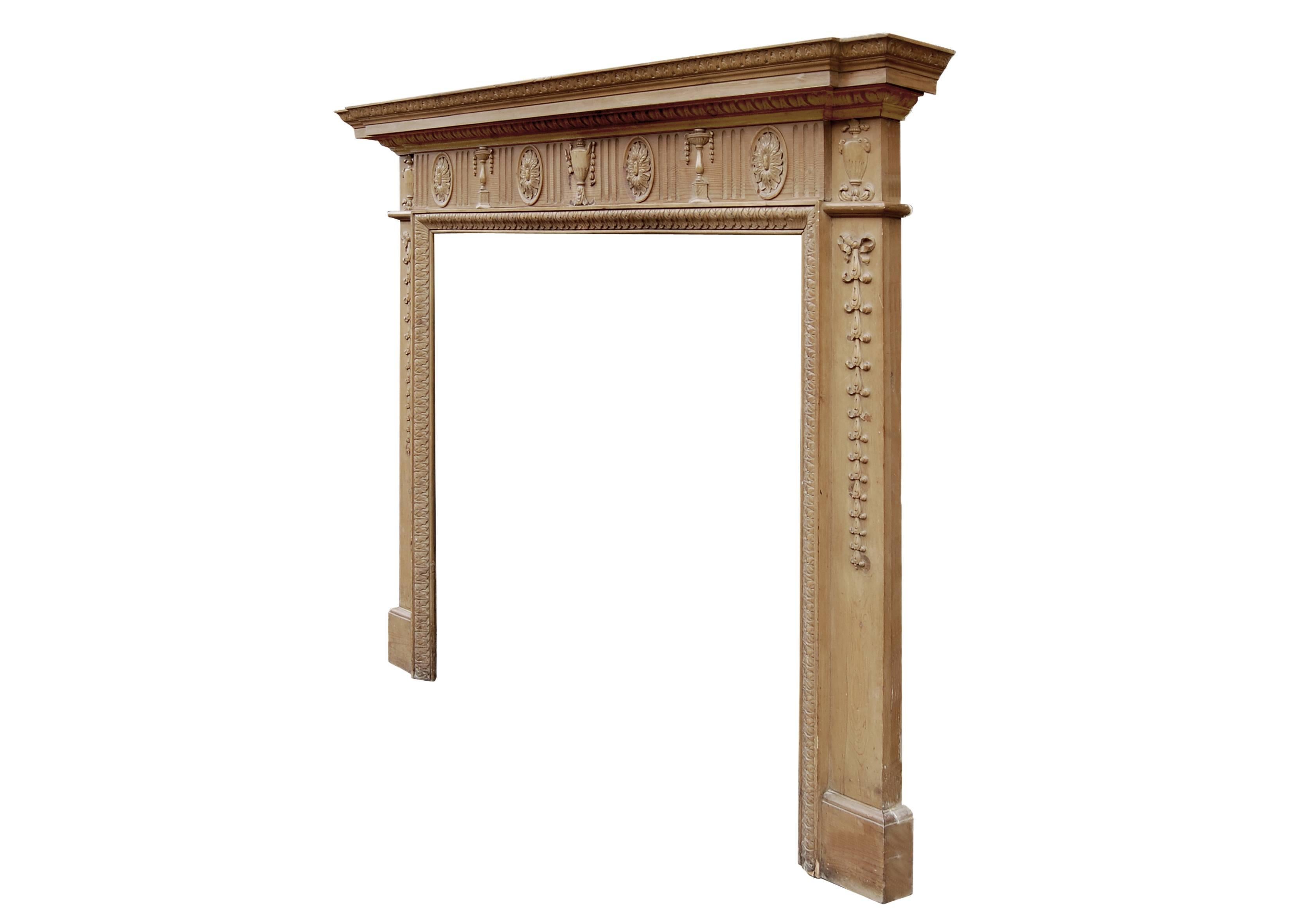 A classical English waxed pine fireplace, the frieze with urns, leaf pateras and flutes, the jambs with bellflower drops and carved leaf leg moulding. Egg and dart and leaf cornice. 20th century.

Measures:
Shelf Width:	1555 mm      	61 1/4