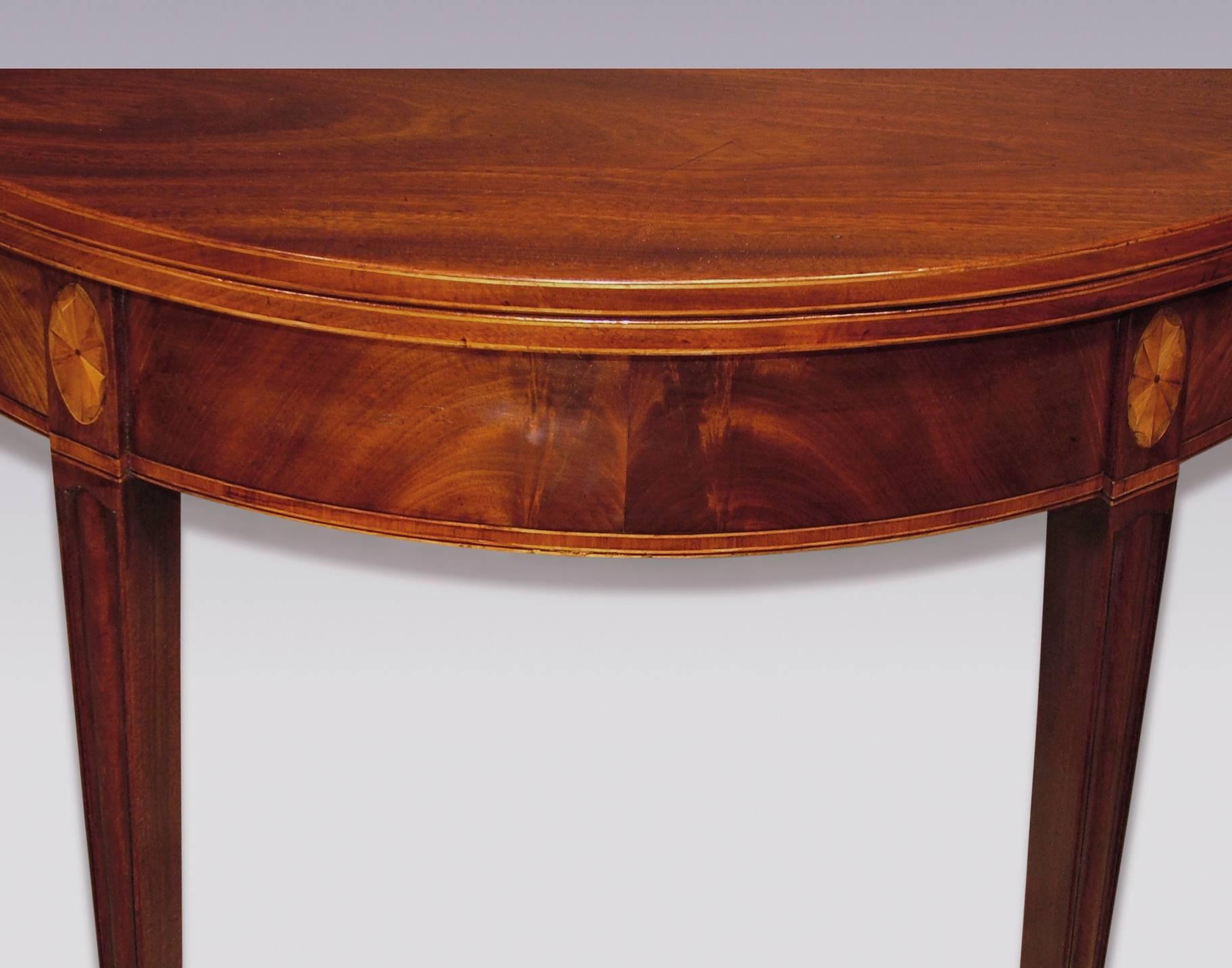 A near pair of late 18th century Sheraton period half-round figured mahogany tea tables, having boxwood strung edges above tulipwood banded friezes, supported on moulded square tapering legs with fan inlays, ending on spade toes.