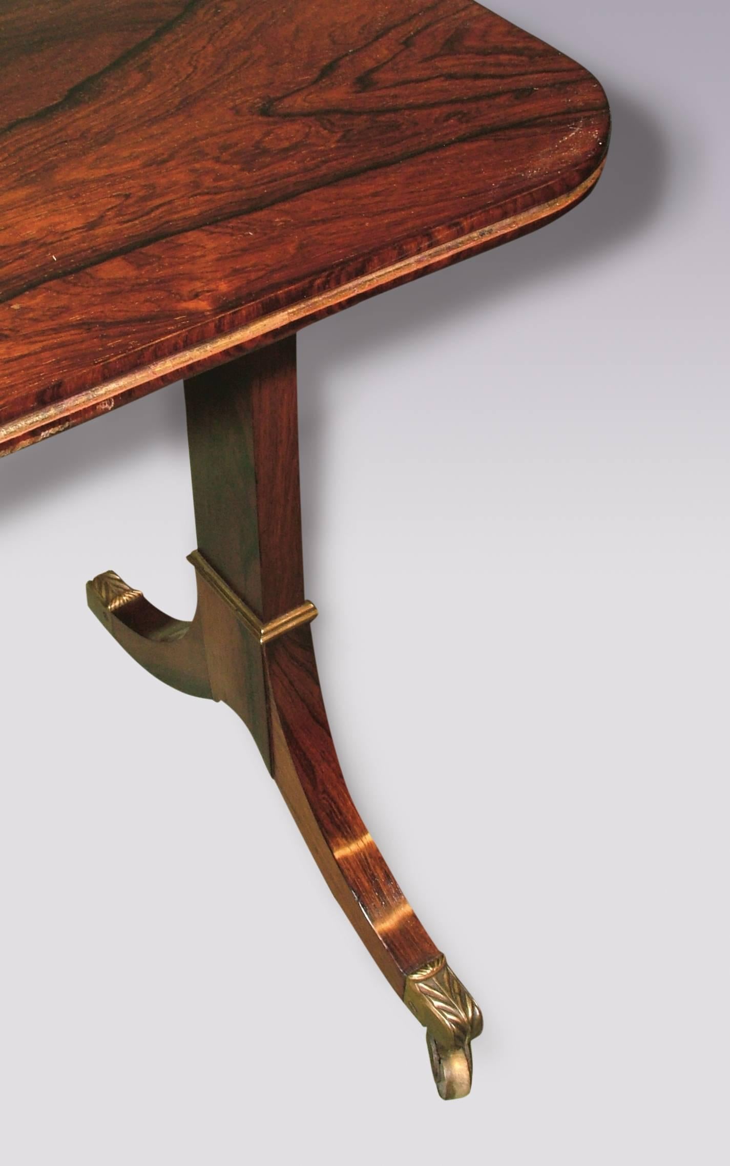 A Regency period figured rosewood side table having reeded edged rectangular top raised on end supports with arched stretcher, ending on swept leg bases with brass castors.