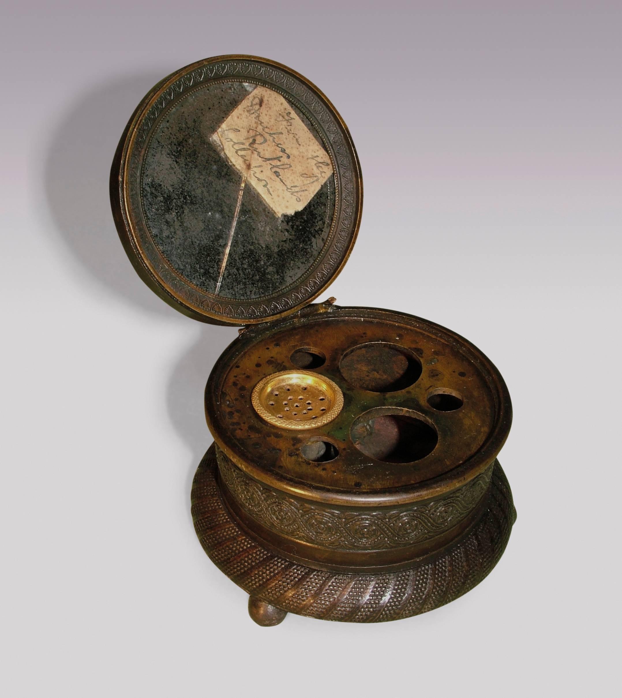 A small early 19th century Regency period circular bronze encrier, engine turned throughout, having pierced mirrored lid, bearing label ‘from the Duchess of Rutland’s collection,’ engine on ball feet.