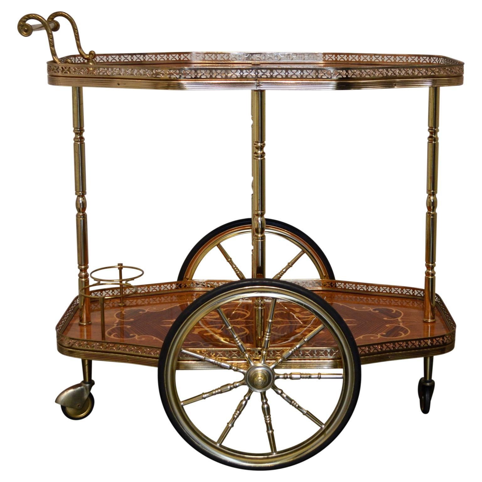 An elegant midcentury Italian serving or bar cart with marquetry decoration and brass trim.

High gloss ribbon mahogany veneer inlaid with a beautifully rendered floral display of blond wood marquetry. Levels joined by brass columns, and handle is