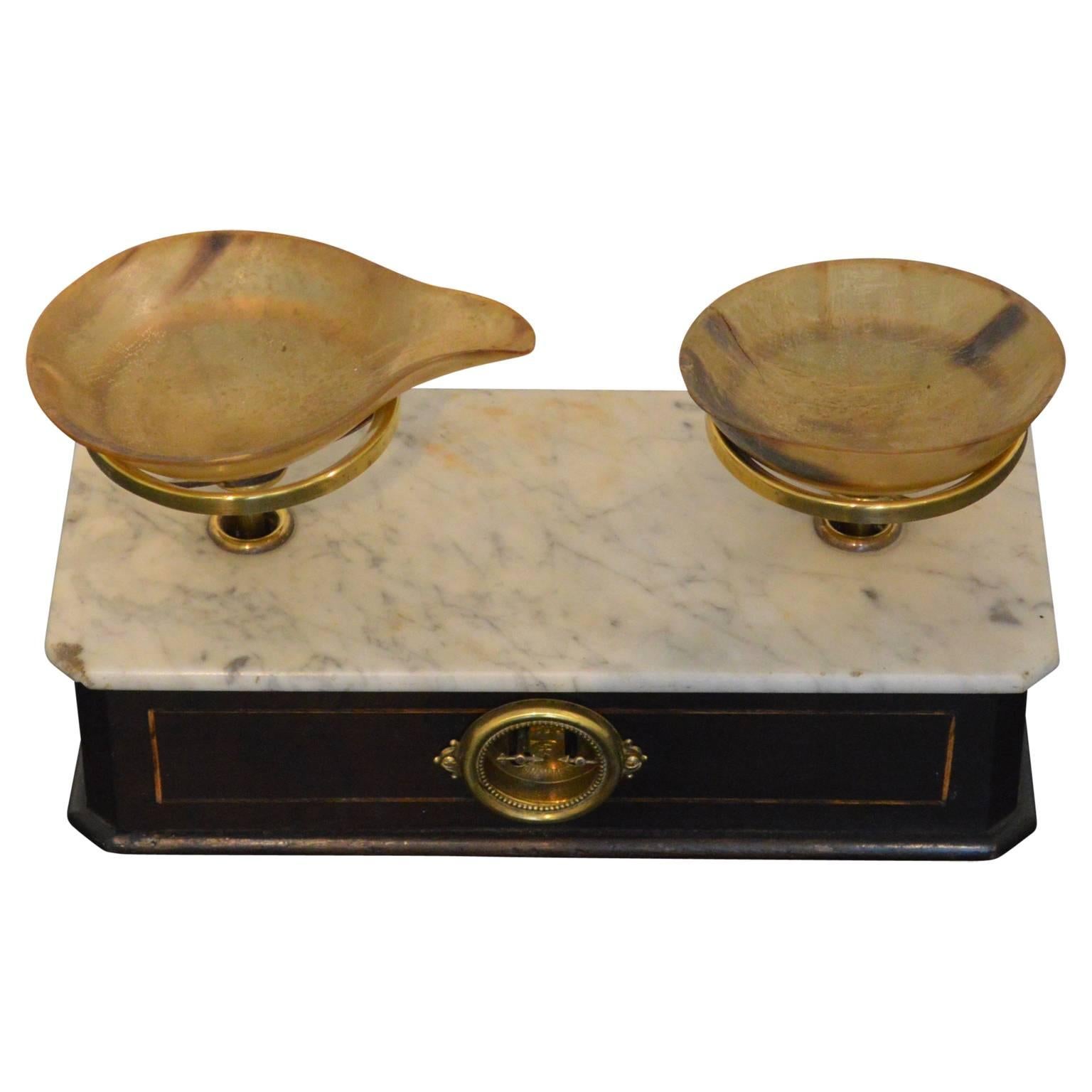 This set of Napoleon III period pastry, or apothecary scales features a double faced ebonized wooden base with a white marble top. Each side displays a set of needles and is indicating the maximum measurable weight. Finished with horn bowls is rare