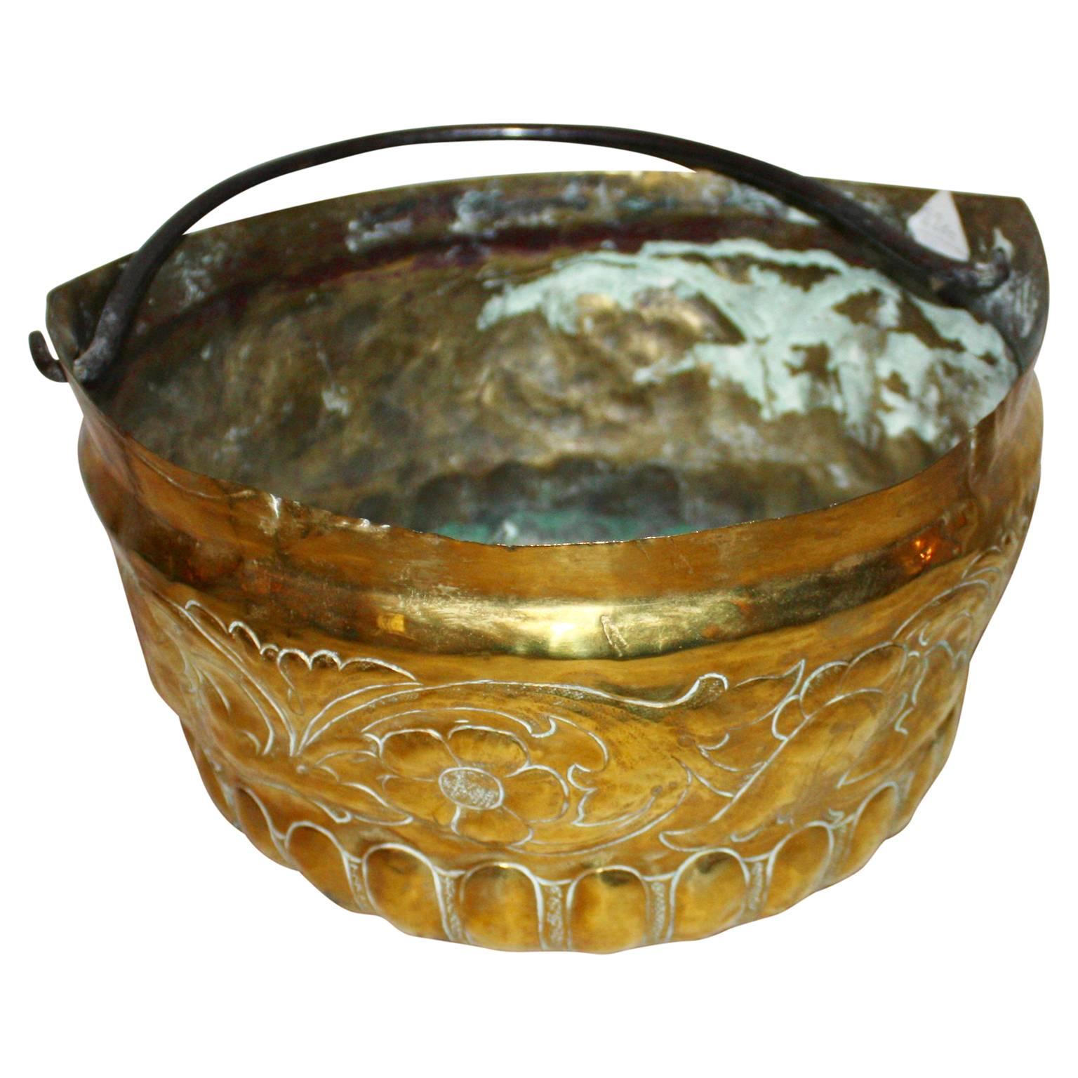 Period brass cooking pot with decorations on the side and bottom. Pot has a iron handle to hook pot over the fireplace.