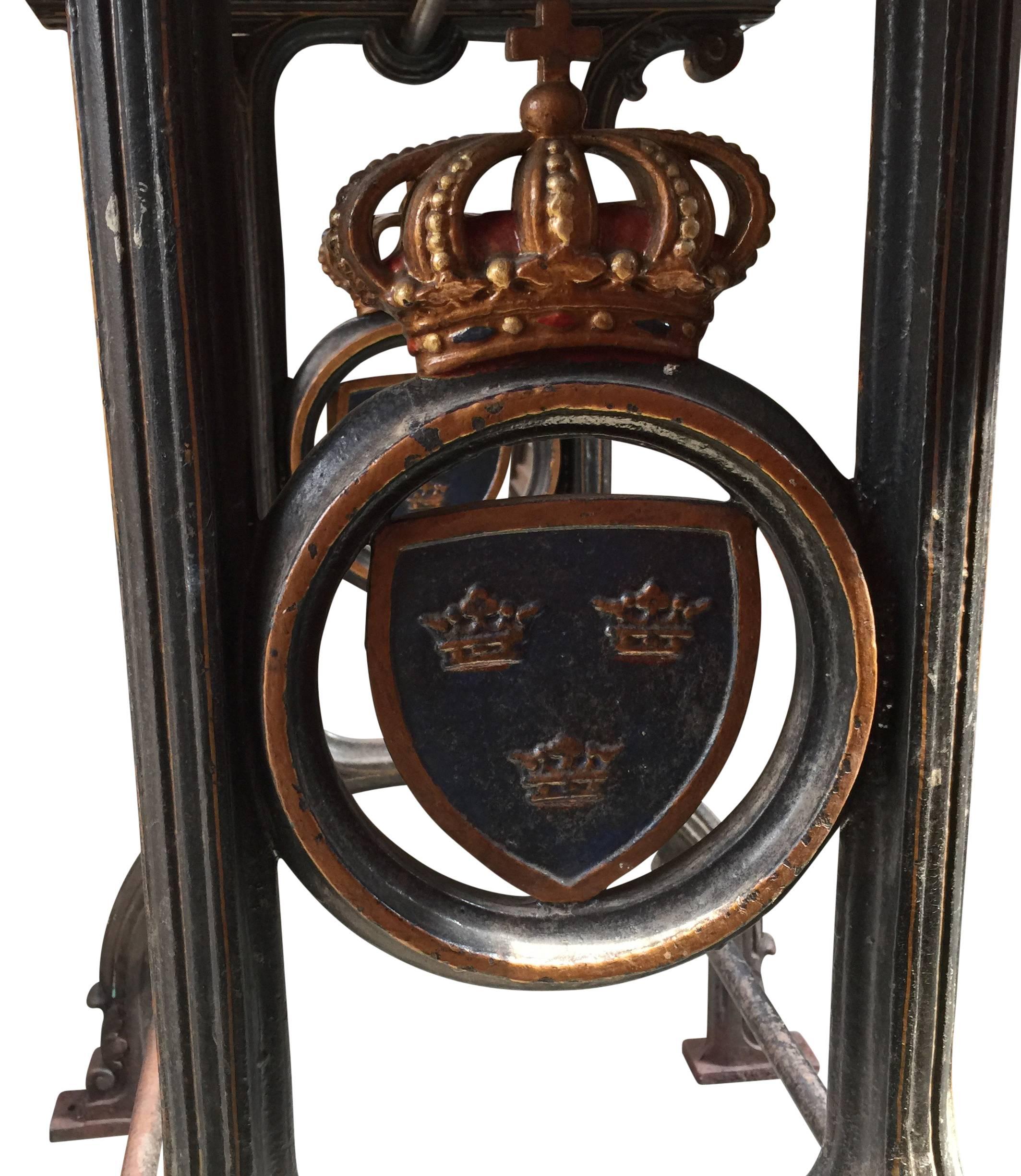 Charmanter Gusseisentisch mit einem gekrönten Emblem mit drei königlichen schwedischen Kronen auf blauem Hintergrund auf jeder Seite.
