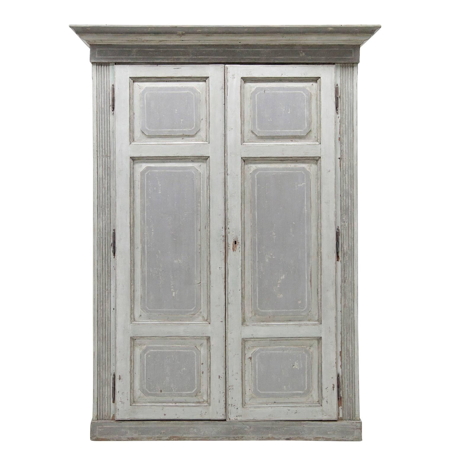 Large, painted Italian cabinet with coffered doors and sides, as well as fluted pilasters at the corners and a multi-stepped cornice.