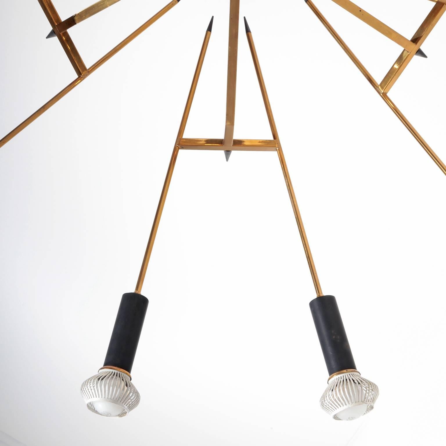 Chandelier by Oscar Torlasco for Lumi with 12 flames. The brass frame consists of 12 arrow-shaped staffs with black spikes and a black cylindrical sockets.