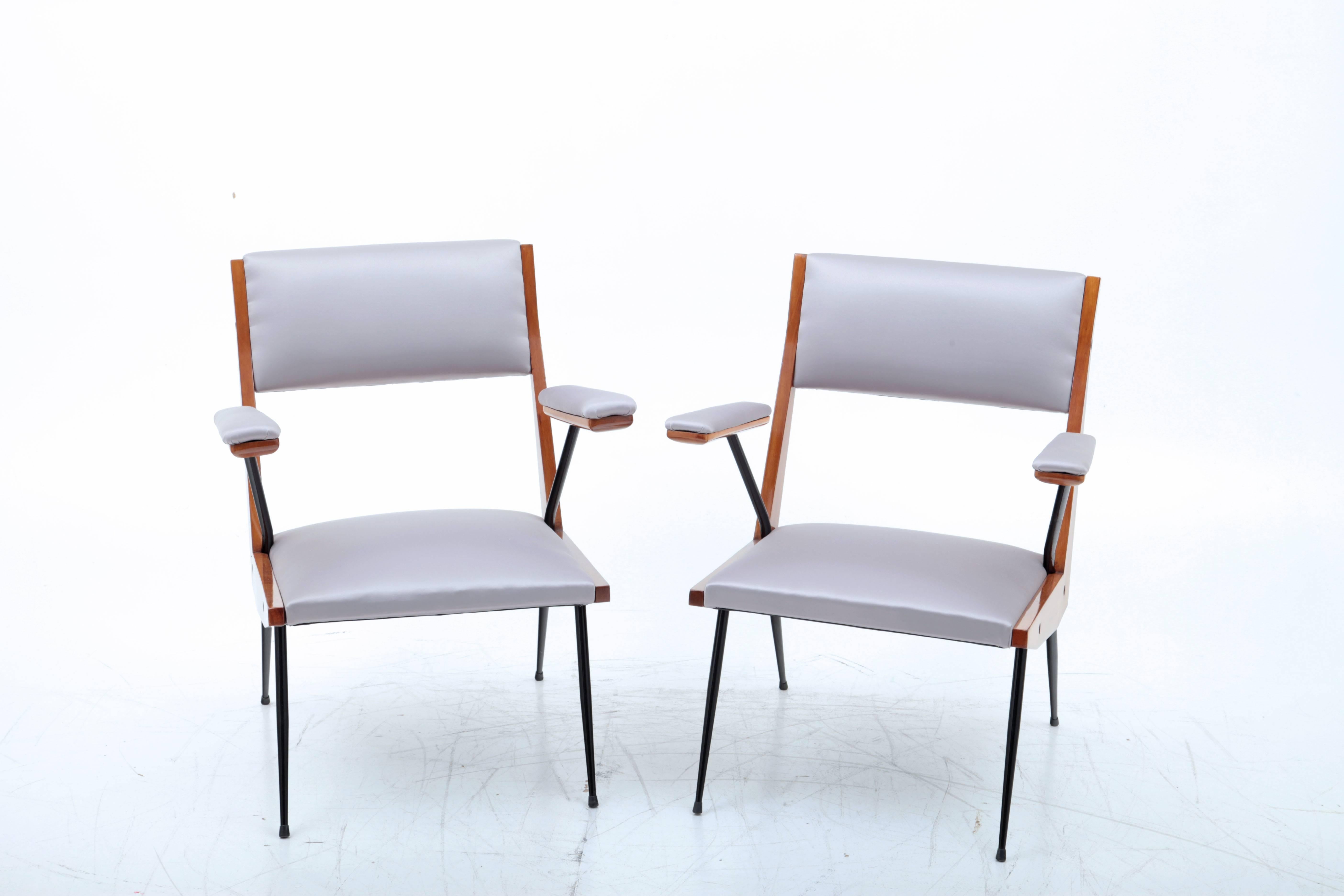 Pair of armchairs with wooden frame on thin, black iron legs and a grey upholstery on seat, backrest and armrests. Very interestingly designed profile.