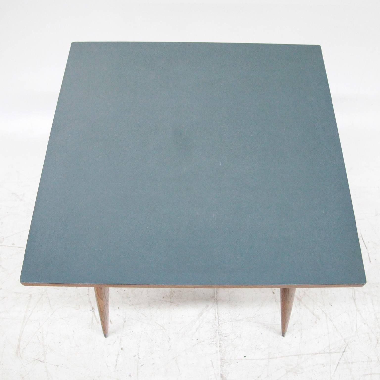 A table attributed to the Italian designer Gio Ponti with a square surface situated on four long conical legs with blackened ends.