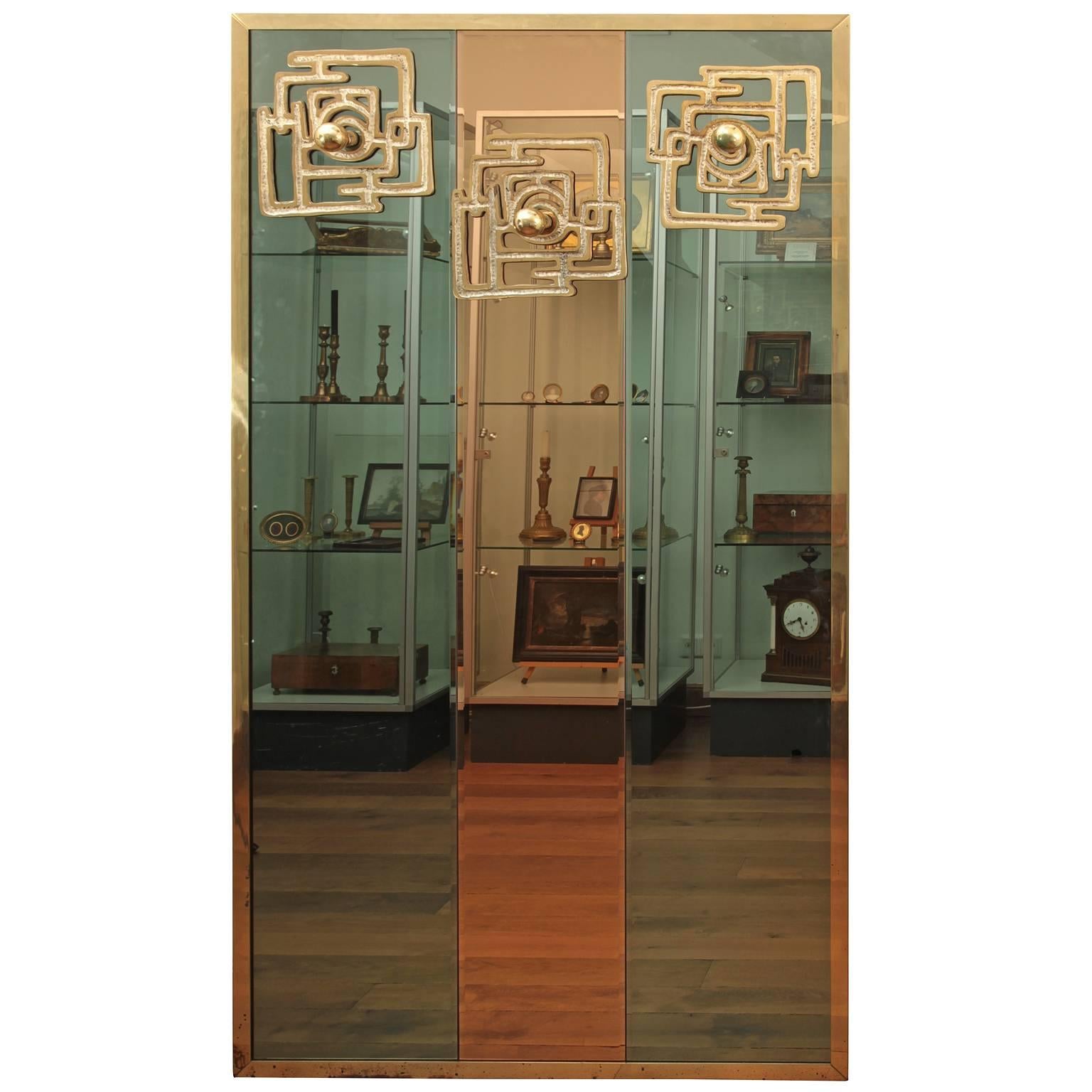 Large rectangular coat rack by the Italian artist Luciano Frigerio. The back consists of three mirror panes in different hues. At the top part of the mirror are bronze appliqués as coat hangers, designed in the typical style of Frigerio.