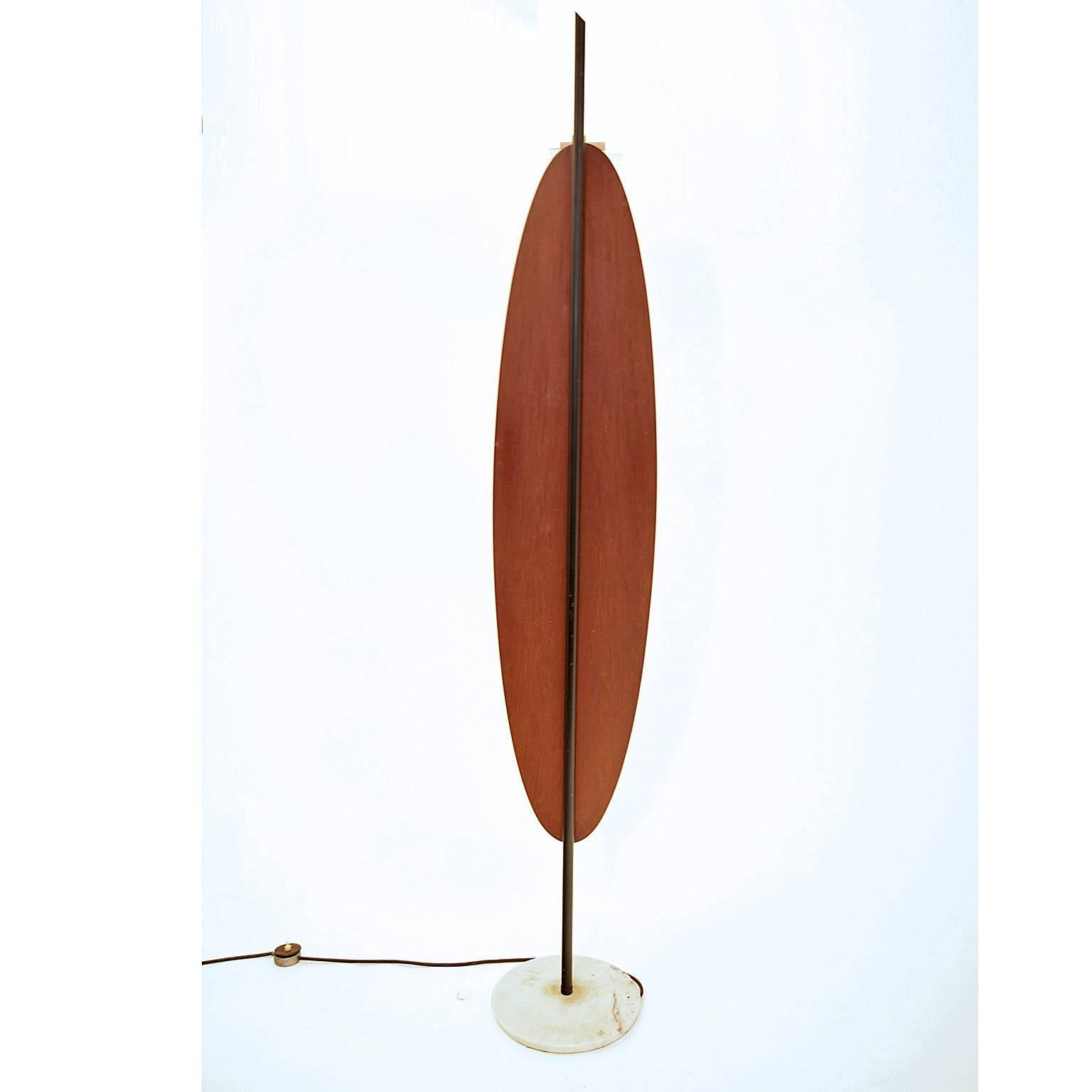 Floor light by Reggiani circa 1960 on a round white marble disk. The oval mahogany structure with three white opaque glass bodies is mounted on a blackend iron rod. The end is slanted. 

See: L'Art Ménager, p. 350.