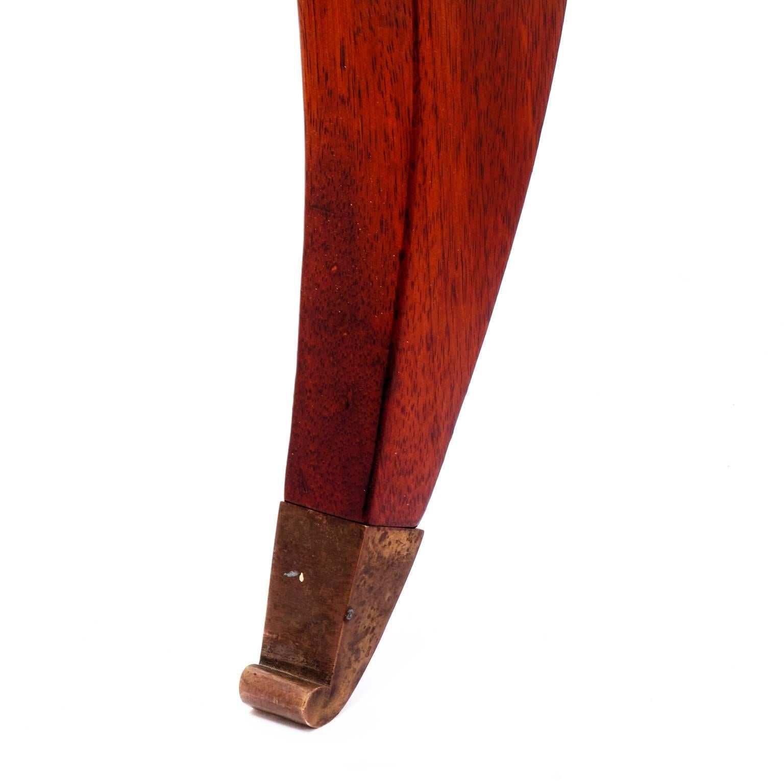 A table on S-shaped legs with brass caps made from polished walnut. Probably from Gino Levi Montalcini from the 1940s. The apron has one drawer which, when closed, sits flush with the apron which is accentuated with a dentil moulding. A new pane of