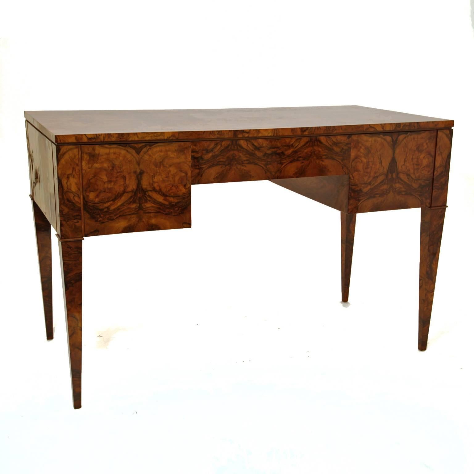 Desk with a beautiful burl wood veneer and five drawers. The desk stands on tapered feet.