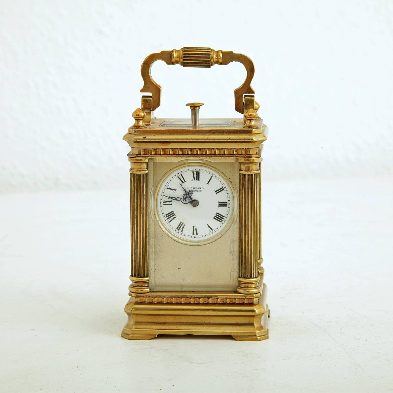 Small travelling alarm clock in a brass case with an enamel clock face and roman numerals. Marked L. Döring Leipzig. The case is glazed on five sides and has fluted columns at the corners. The clockwork is signed 