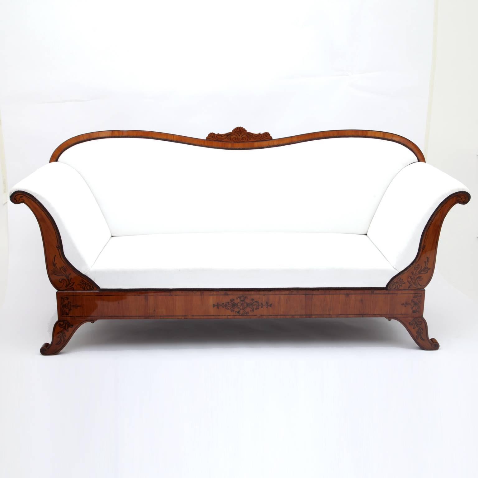 Elegant Biedermeier sofa on tapered legs. Curved backrest with s-shaped armrests. Lower rim, legs and armrests are decorated with floral motives in Schwarzlot.