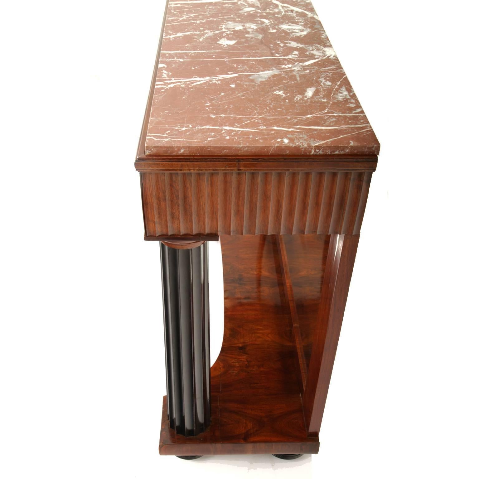 Neoclassical console table on ebonized ball feet and ebonized columns with fluted shafts. The rim is fluted as well. The back wall is mirrored, the top is red marble, and both are secondary.