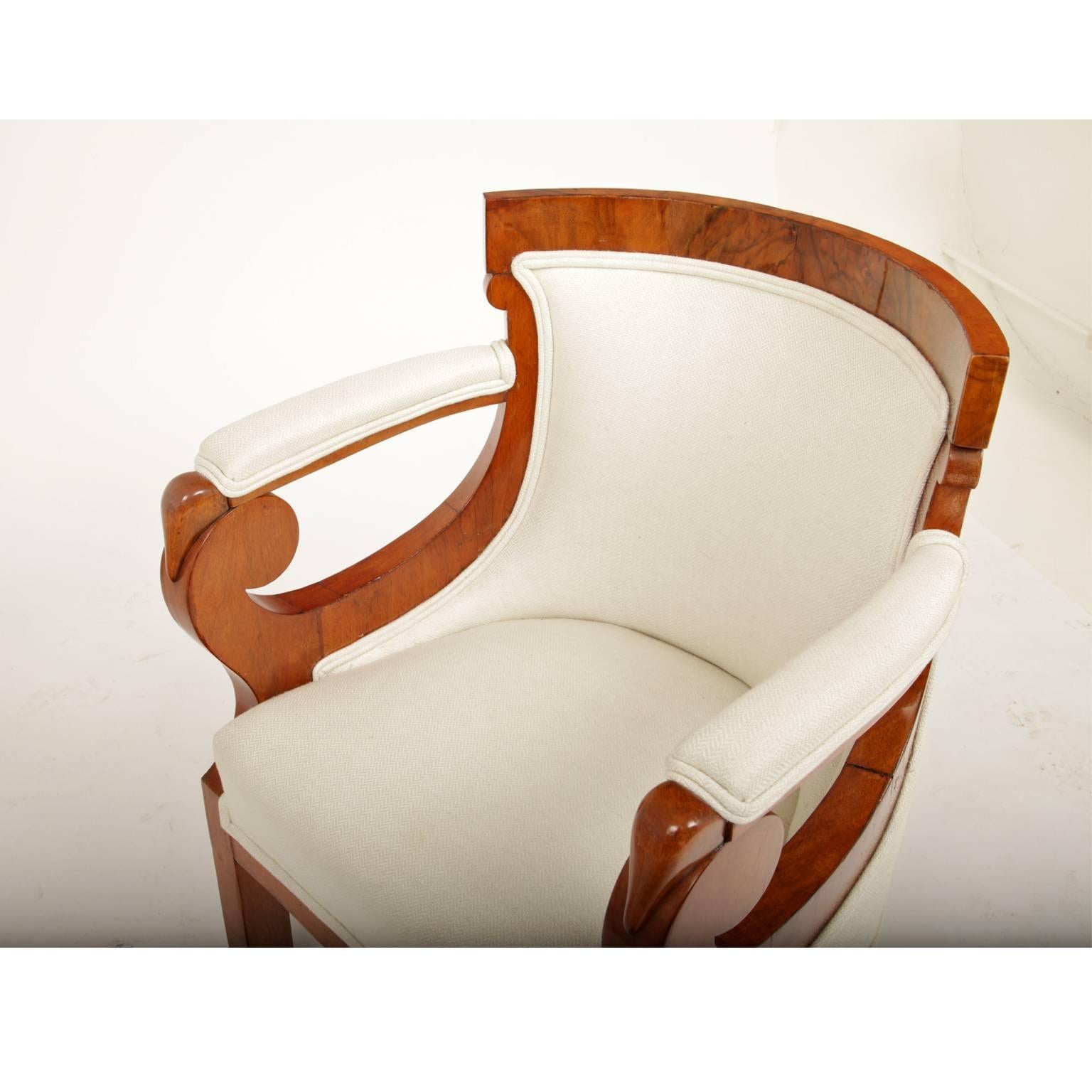 Pair of Biedermeier bergere chairs with unusually designed armrests. The backrest is curved and covered in a crème colored fabric. Seat, backrest and armrests are upholstered.