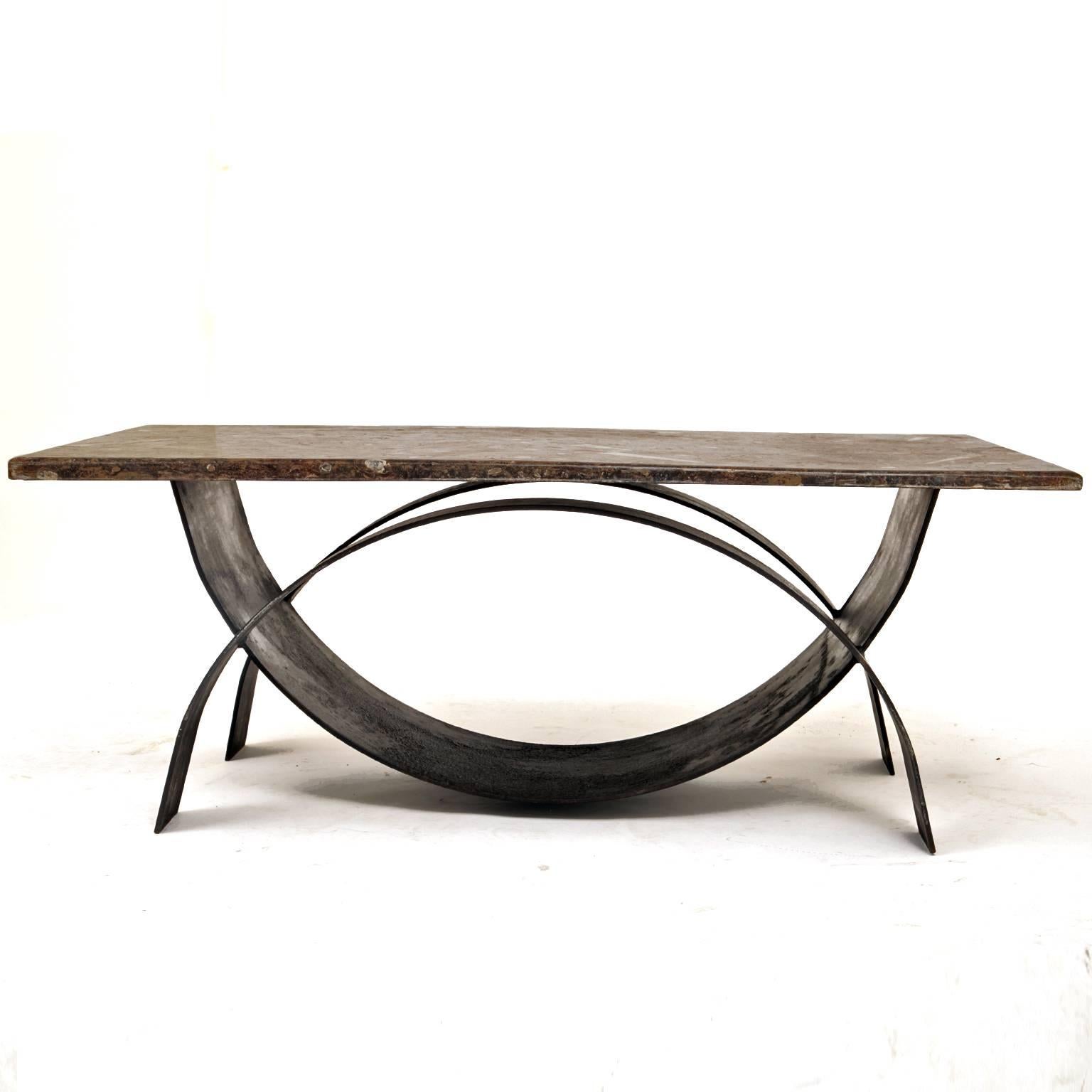 Modernist coffee table with a bent iron frame and a tabletop out of fossil stone.