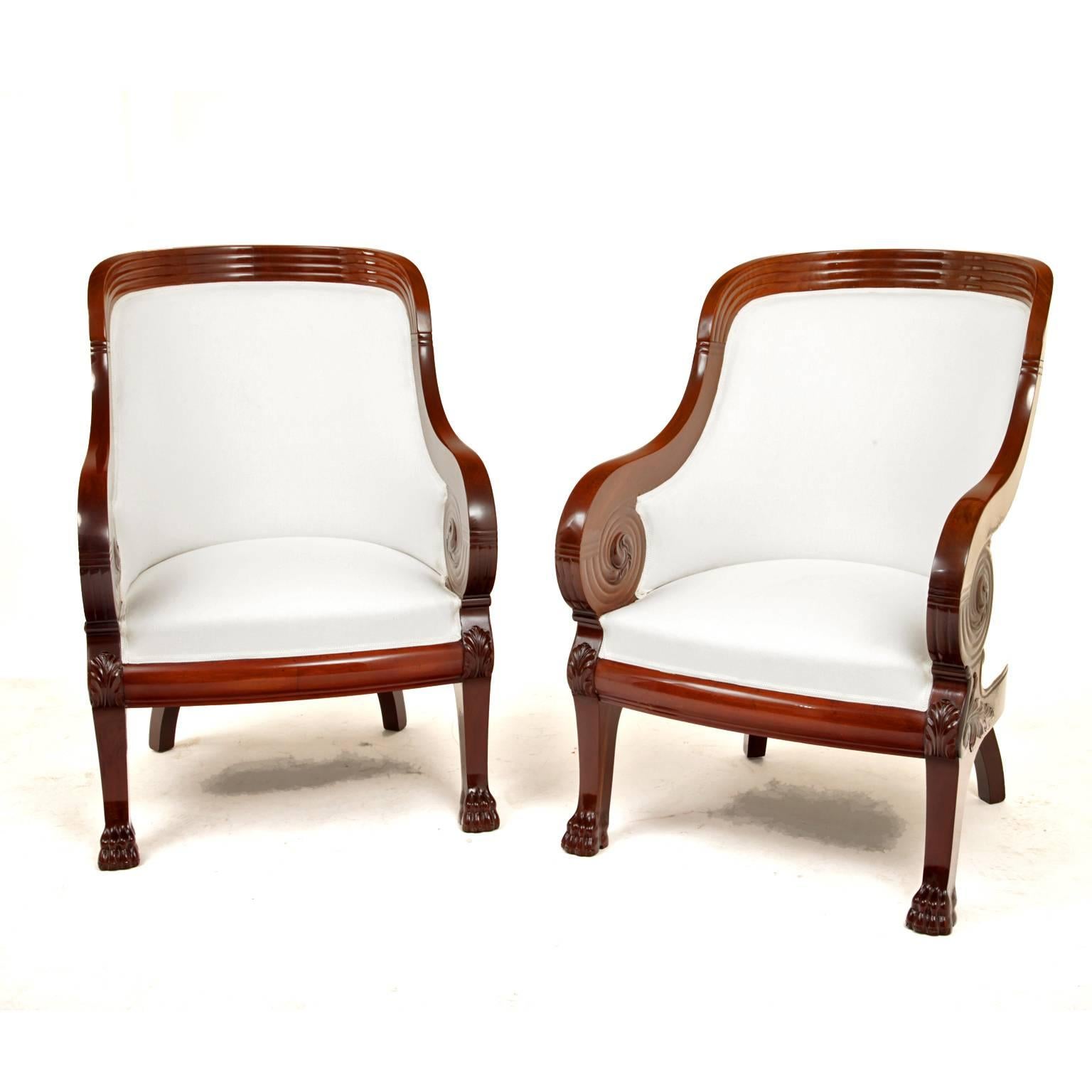 Pair of armchairs on lion's feet with scrolled armrests and a curved backrest.