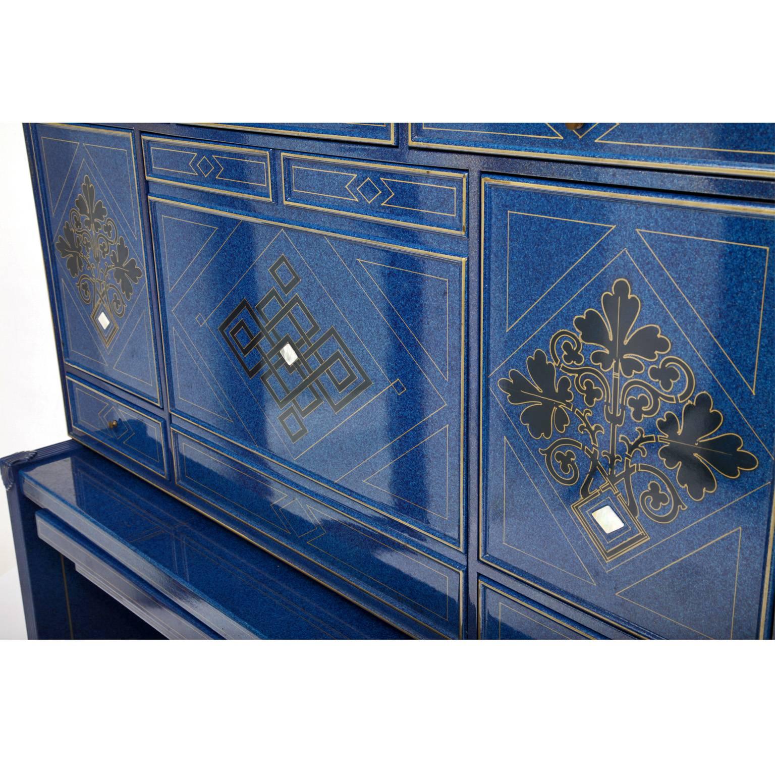 Unusual secretaire, lacquered in blue with rhomboid and leaves decor. The top has a foldable writing surface and several drawers and compartments. The large drawer underneath has the manufacturer's label inside. The lacquer is original and shows