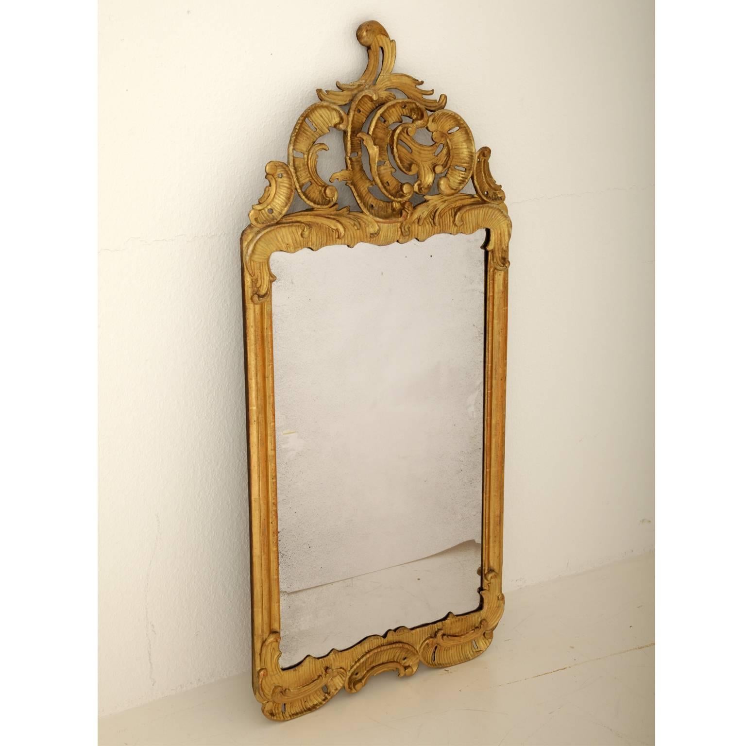Gilded wall mirror with asymmetrical rocaille decor. The mirror pane is slightly spotted.