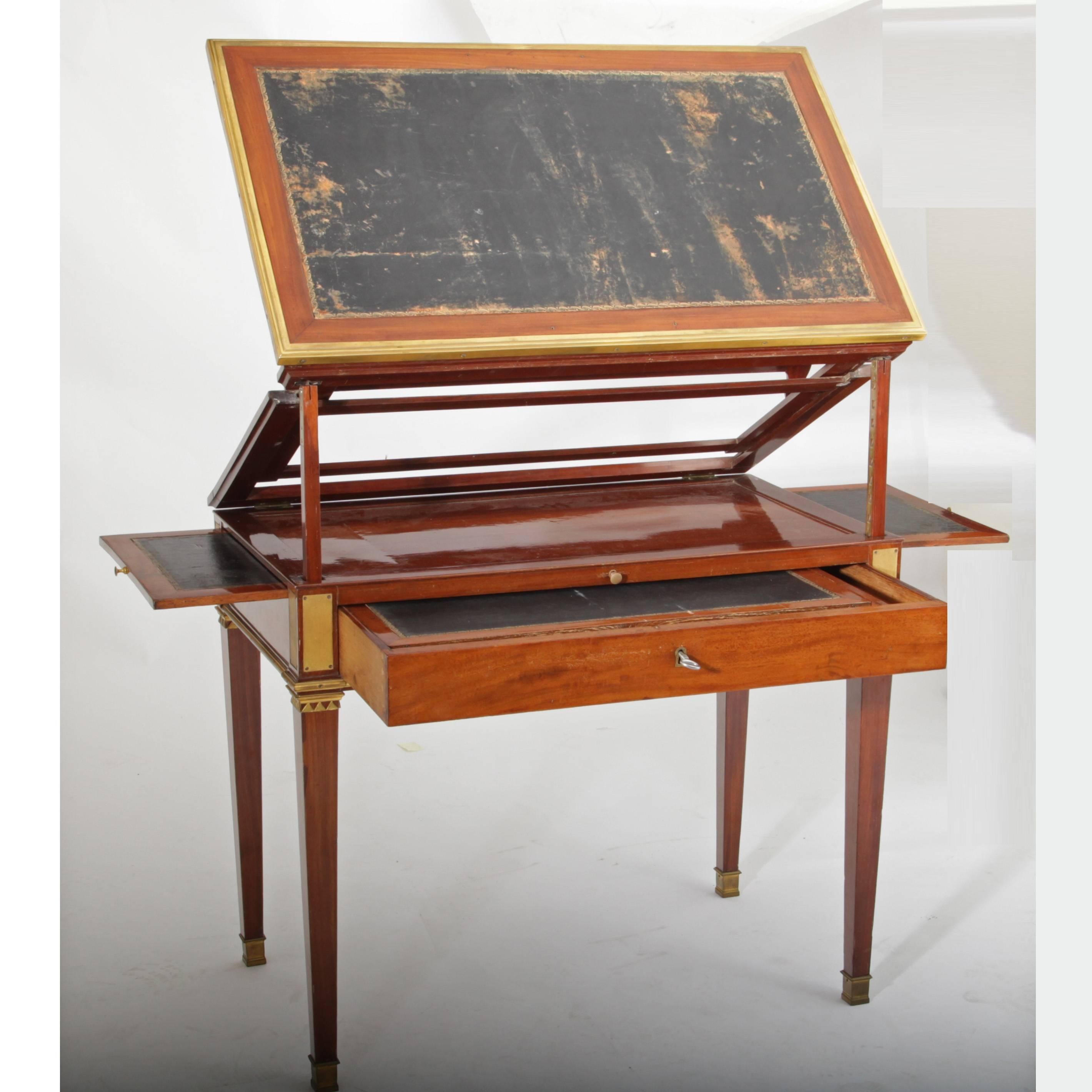 Writing desk with height adjustable writing surface, laterally extendable as well. The desk stands on tapered feet with brass sabots. The writing surfaces are covered in black leather. 